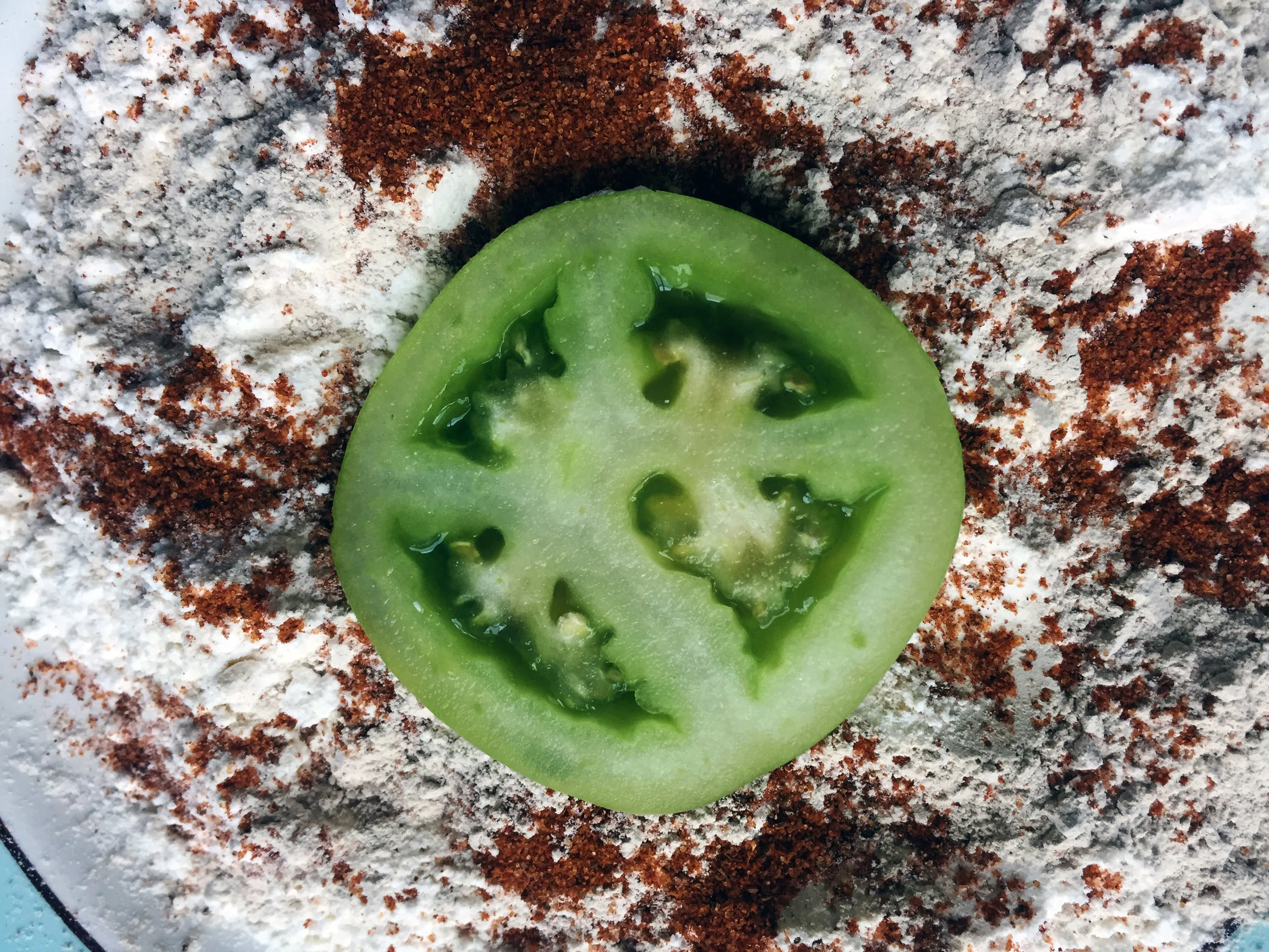 5. Now, we will begin to coat the tomatoes. Frist, coat each side well with the flour and spice mixture.