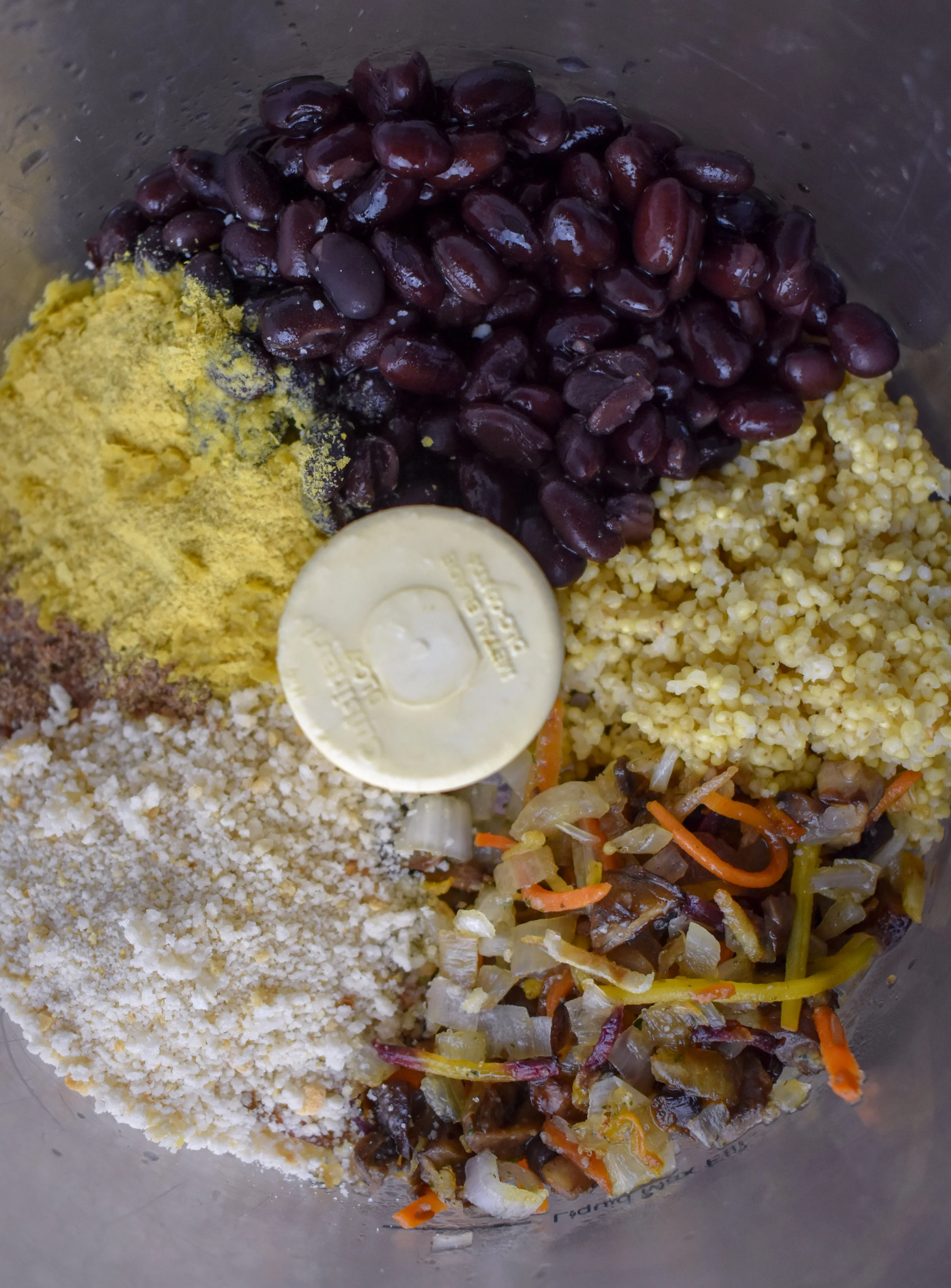 2. Place millet, black beans, mushroom mixture, breadcrumbs, nutritional yeast, spices, flaxmeal, aminos, and lemon juice into food processor. Pulse until well mixed roughly 9-10 times. The mixture should stick together very easily and leave just a tiny bit of residue on your hands.