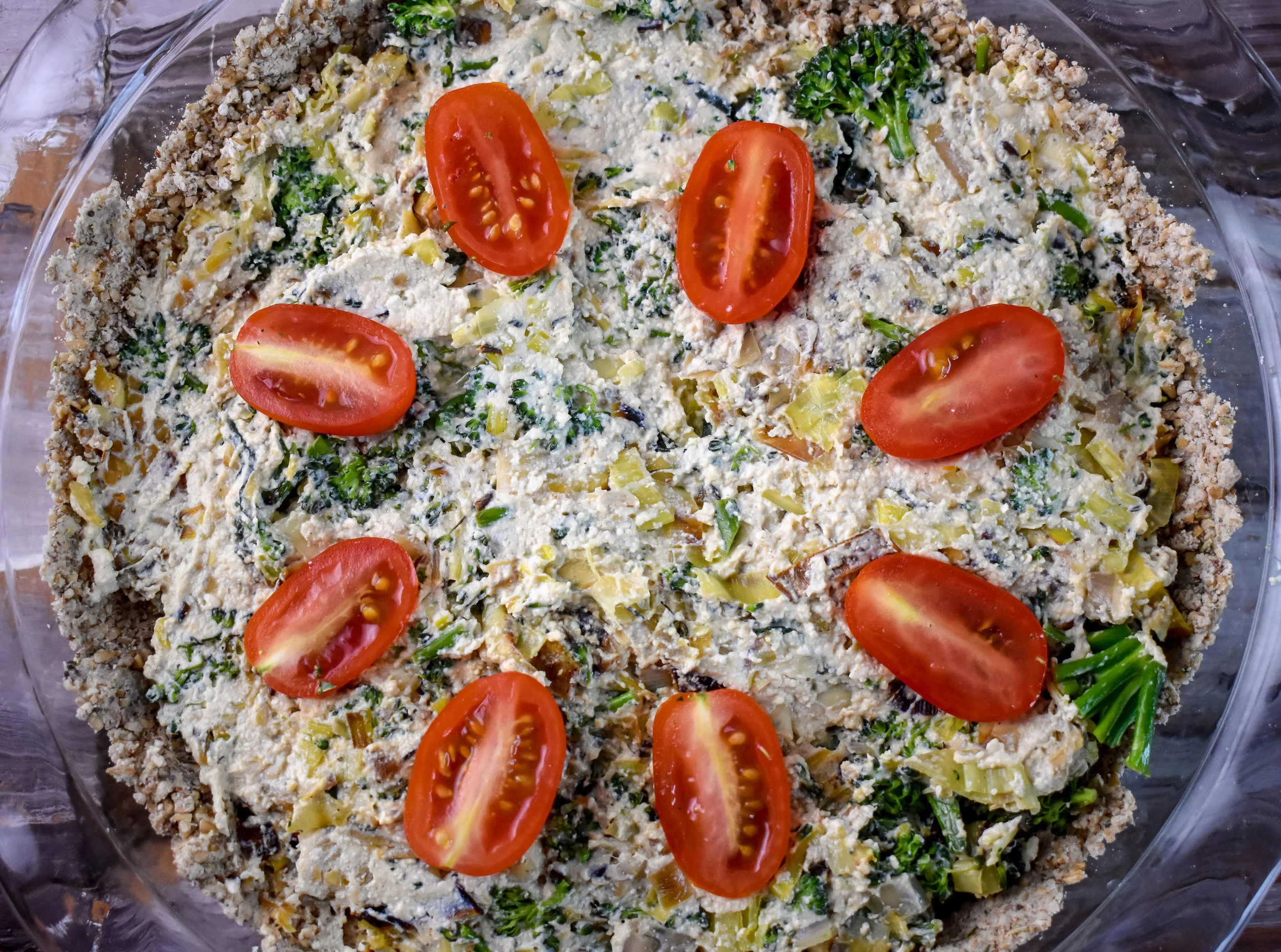 10. Spread the tofu mixture across the crust that has been baked and I like to place a few tomato halves on top of the quiche for some added flavor.