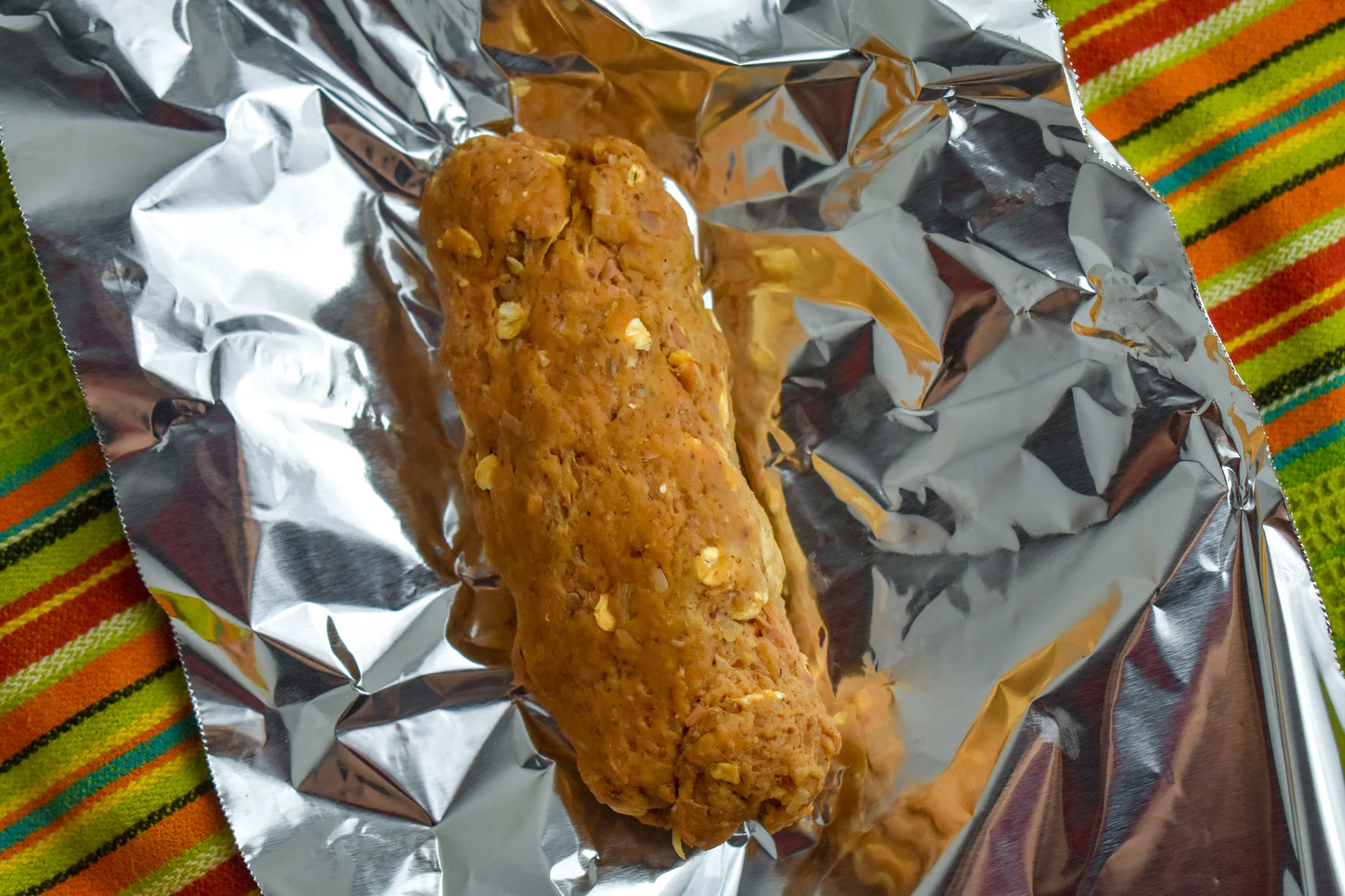 4. Cut the chorizo dog mixture into four equal parts and roll it in your hands until you have an oversized hot dog shape. Rip off four pieces of aluminum foil about 6 inches long and place the dogs in the middle of the foil.
