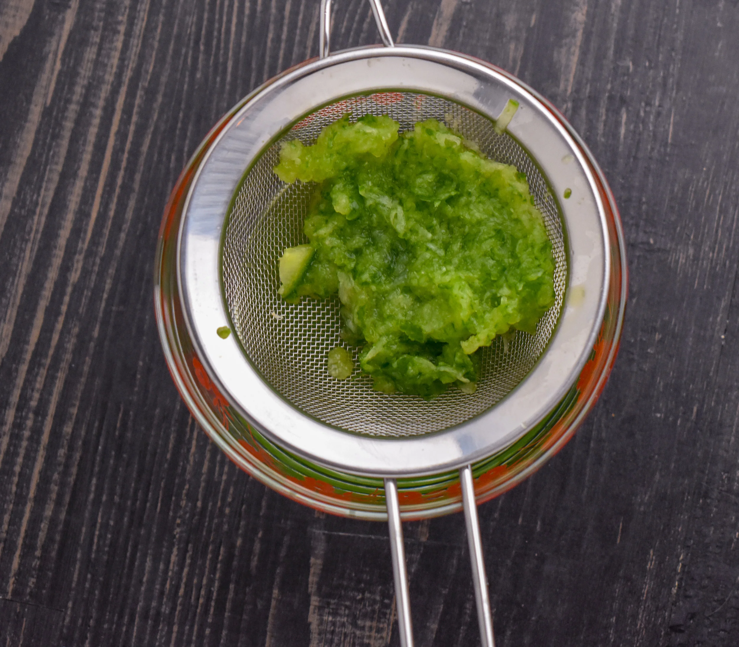 4. While the seitan bakes, we will begin work on the tzatziki sauce. First, grate the cucumber into a mesh strainer over a small bowl. If you don't have a strainer, grate onto a paper towel, cover with the paper towel and wring out the water over the sink.