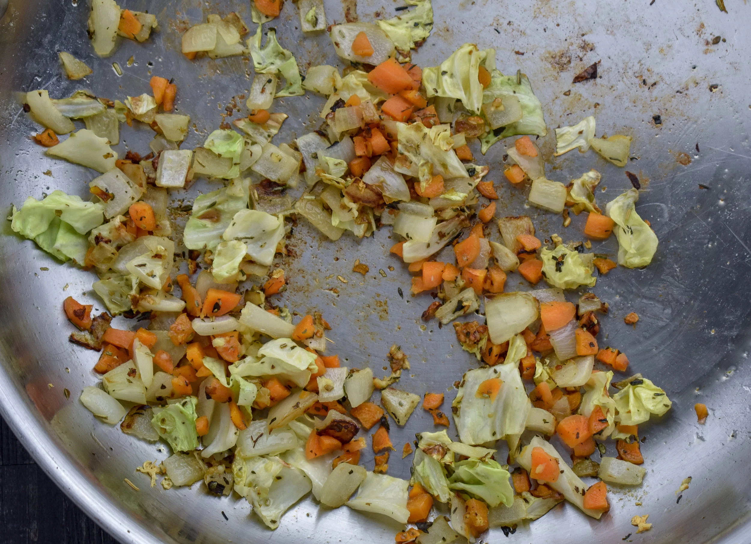 6. As the seitan continues to bake, we will work on the rest of the spring roll filling. Add oil, onions, garlic, and cabbage to a large frying pan. Cook over medium heat for 3-4 minutes, add carrots and continue to cook for another 3-4 minutes. At this point, mix together the chia meal and water, set aside.