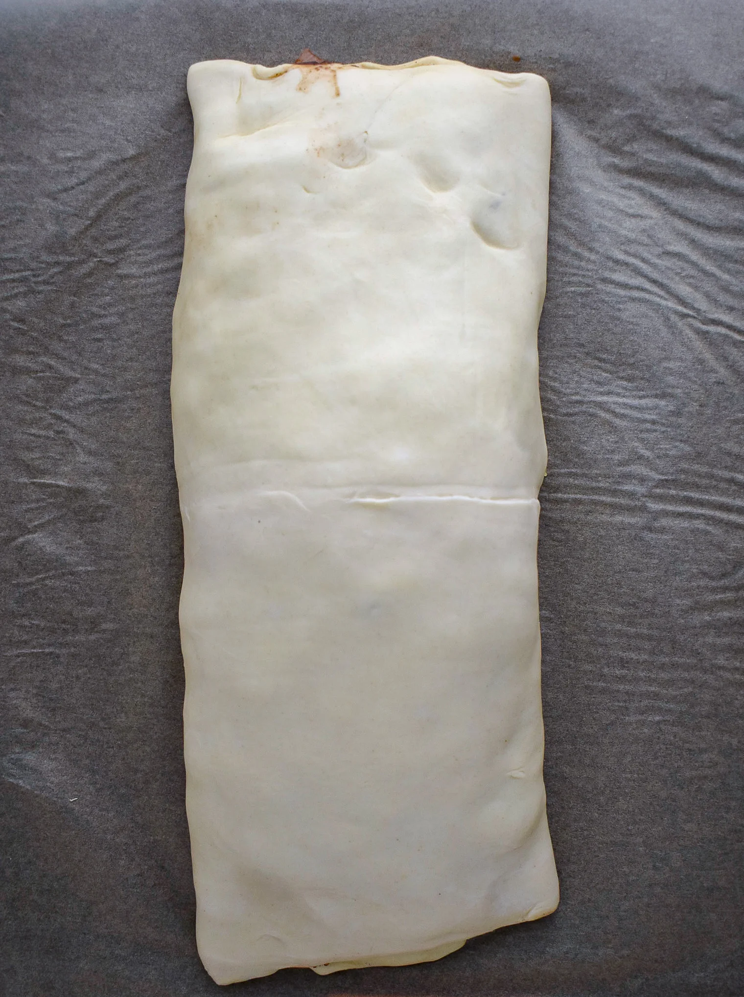 5. Next, we will roll the puff pastry. Take one side and cover the mushroom mixture with one half. Then take the other half and cover the other half. Use a little water on your fingertips along the seal.