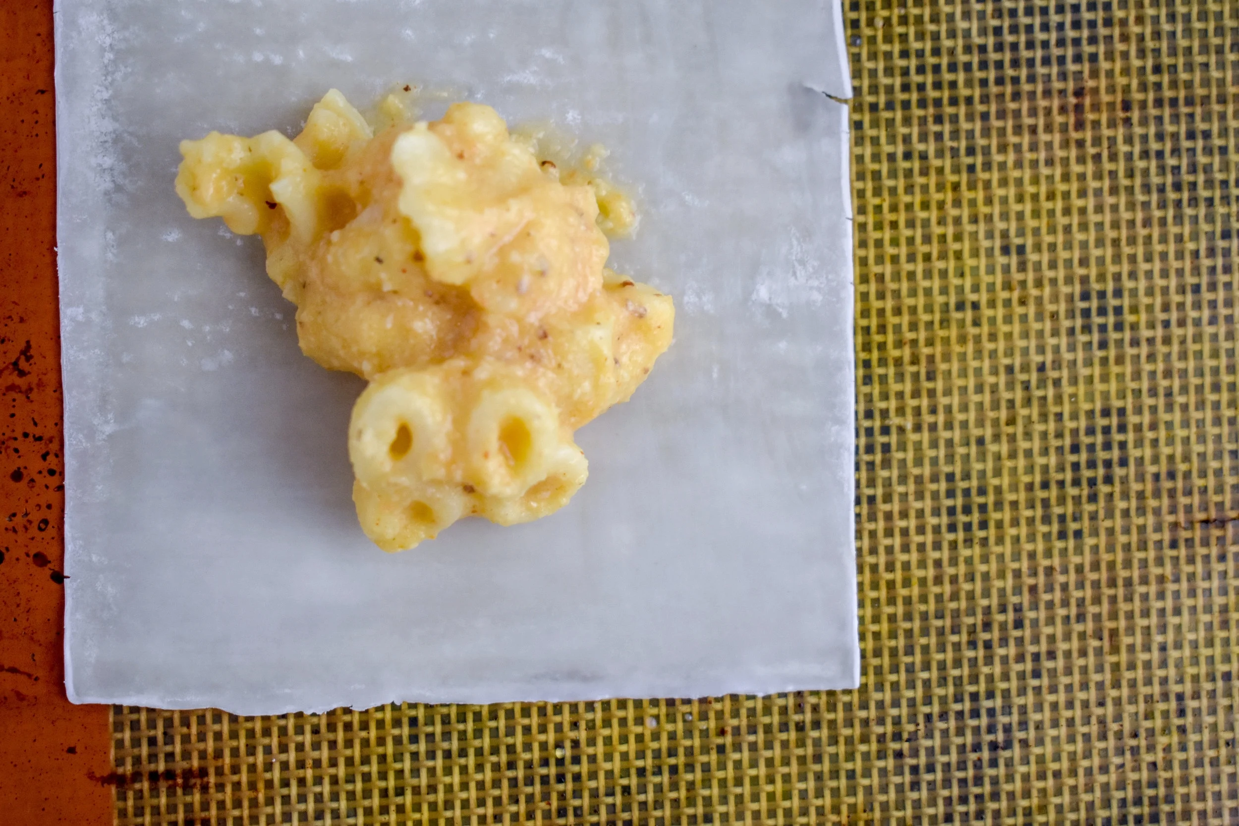 6. While the wrapper is still wetted, scoop one tablespoon of the mac + cheese into the middle of the wonton. 