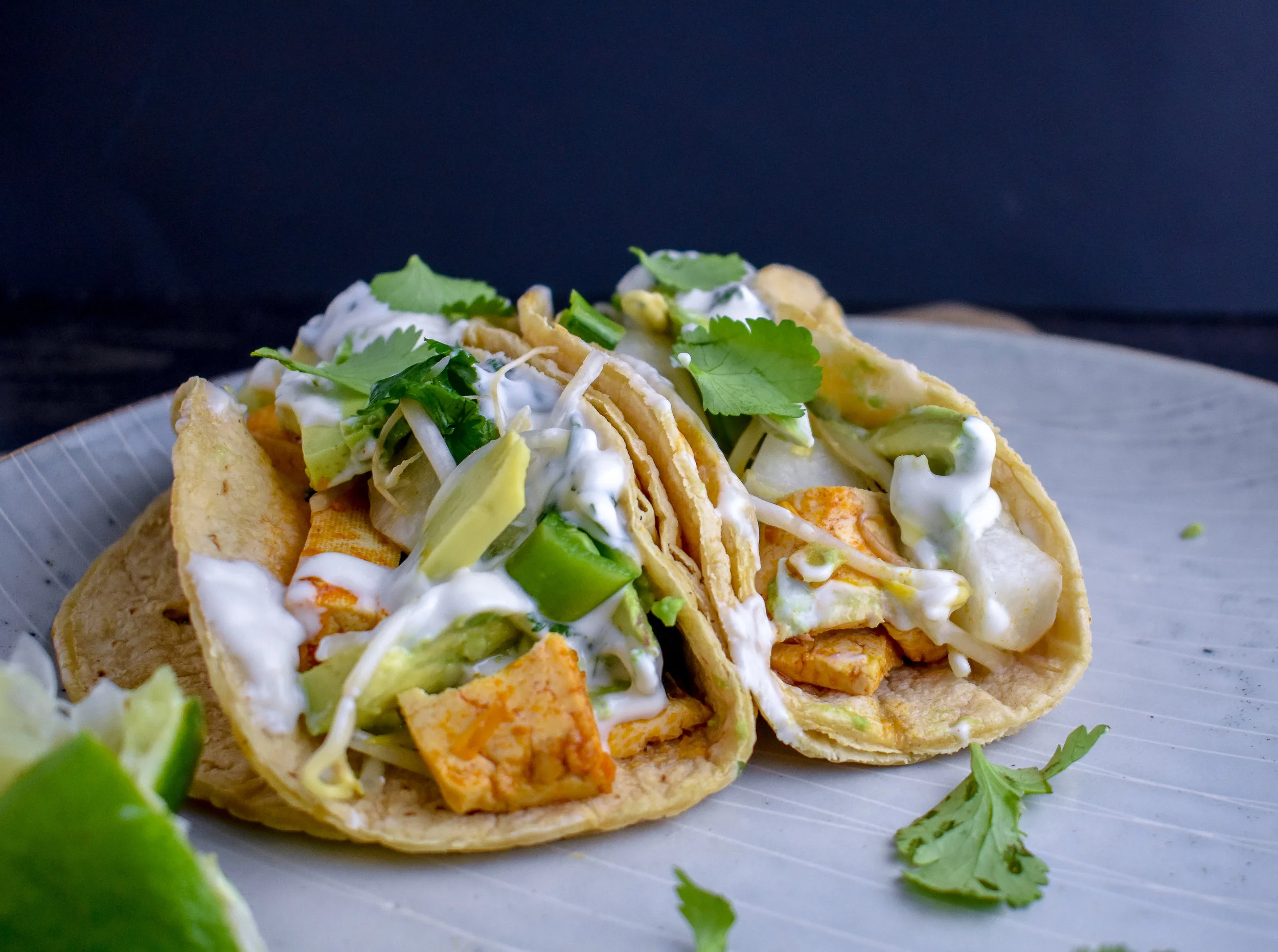 6. To form your tacos. Layer on some tofu strips, slaw, avocado slices, and the aioli. Top with a few pieces of fresh cilantro and a squeeze of lime juice to take it to the next level.