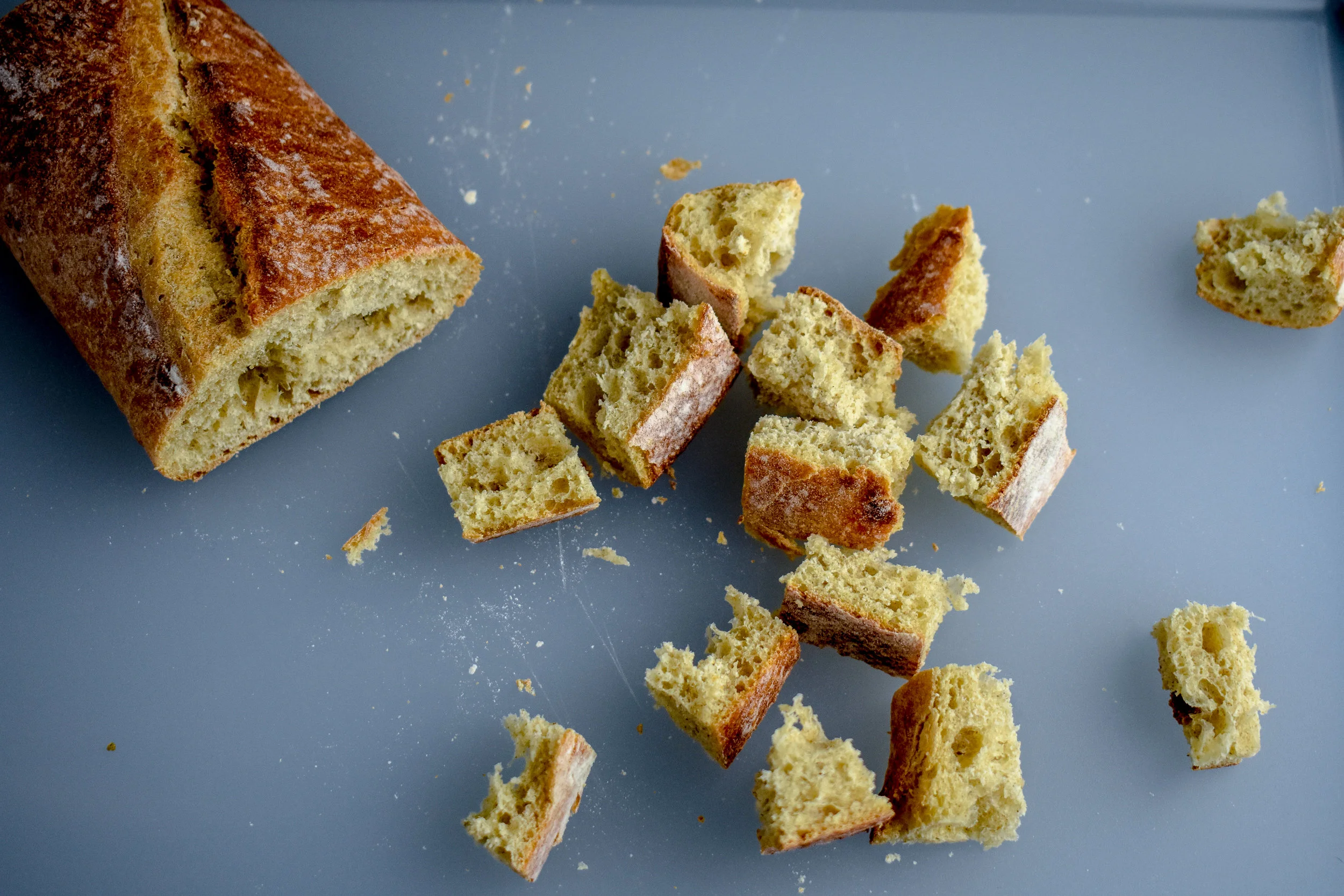 1. While we pull some of the excess water out of the tofu, let's start by chopping up the Italian bread into bite size chunks. Warm two tablespoons of vegan butter in a medium frying pan. 