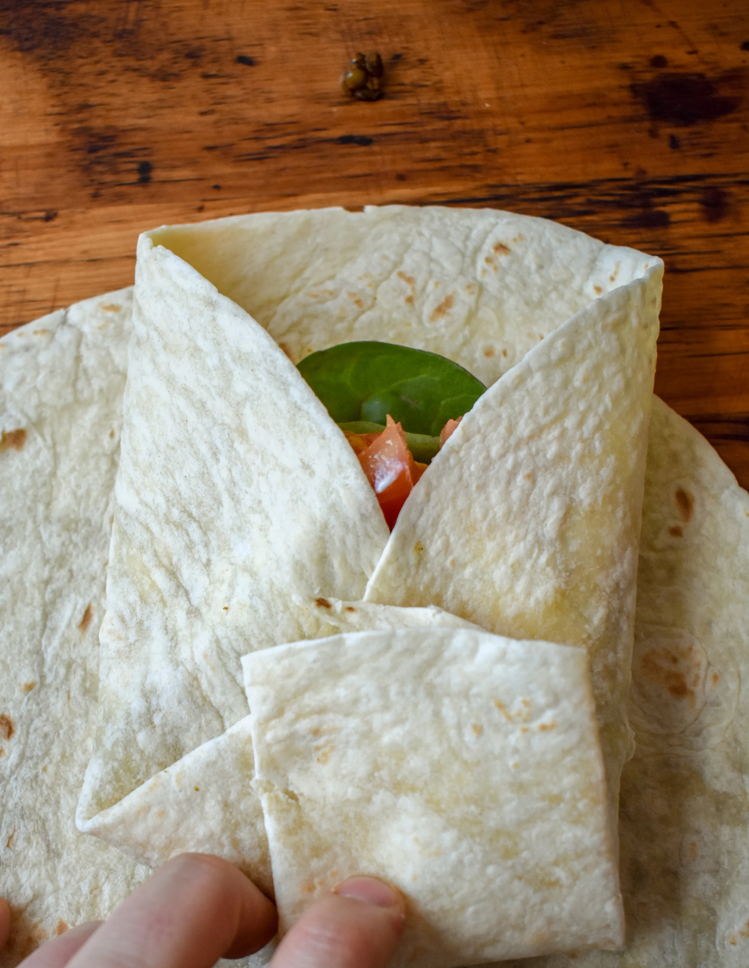 9. Before folding the wraps, put a dry medium pan on medium heat. To wrap the crunchwrap, fold over the edge of the tortilla around the tostada. My tostada was actually too big, so I broke some of the edges off of it to make it smaller. Once it is folded over, move to the pan and place in the pan. 