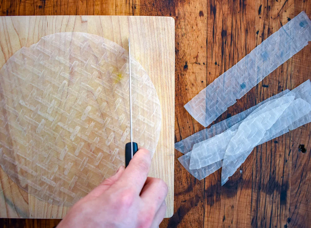 3. While those ingredients cook, let's get working on the bacon. place spring roll on cutting board, and slice each sheet into 5 equal width pieces. I use a very sharp knife. If the sheet is cracking on the edges flip it over...usually one side is easier to cut. Apply a good amount of pressure and use a very sharp knife.