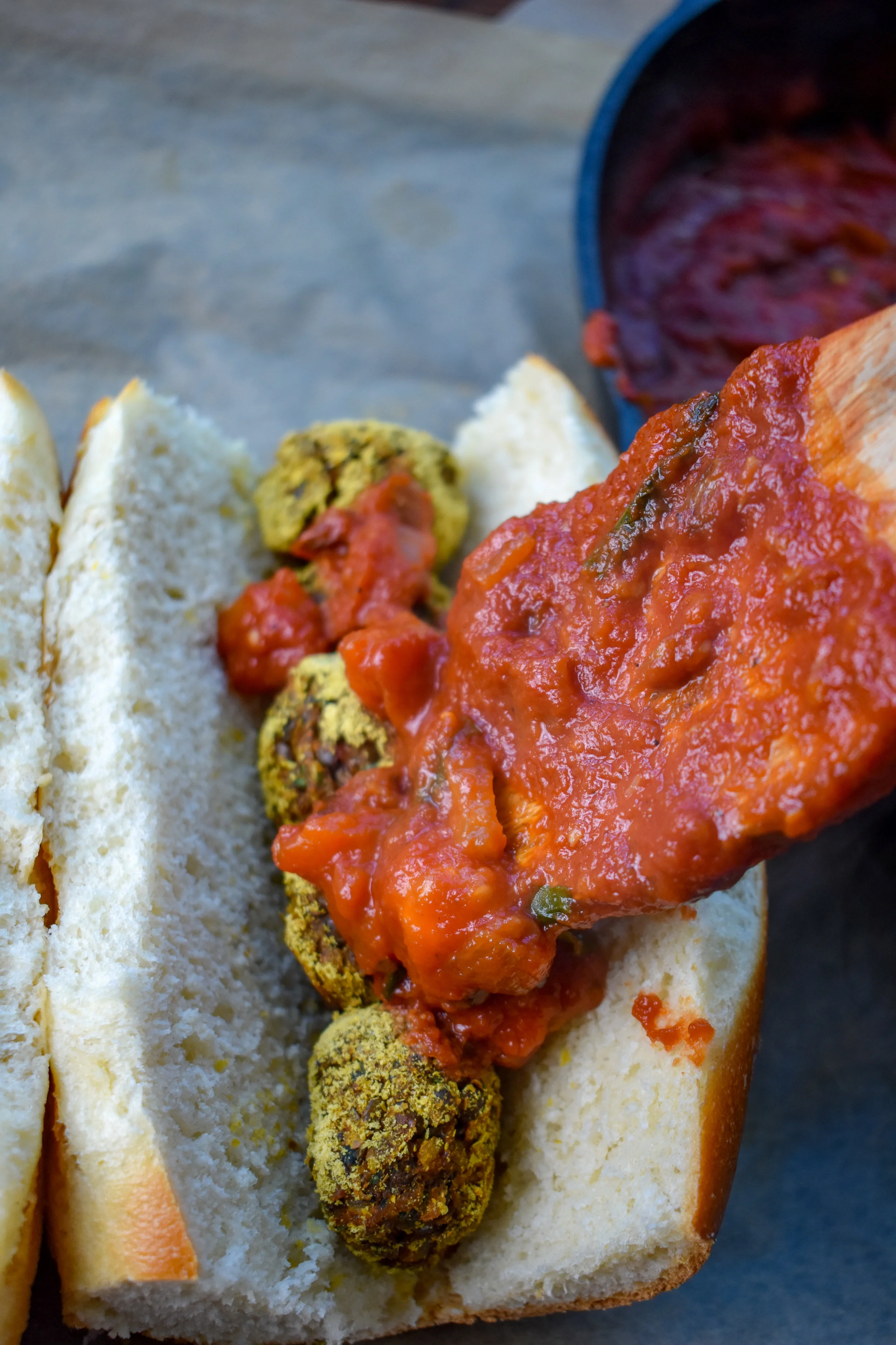 8. To form the sub, slice the hoagie in the middle. Place in the balls (5 of them). Drench in the sauce.