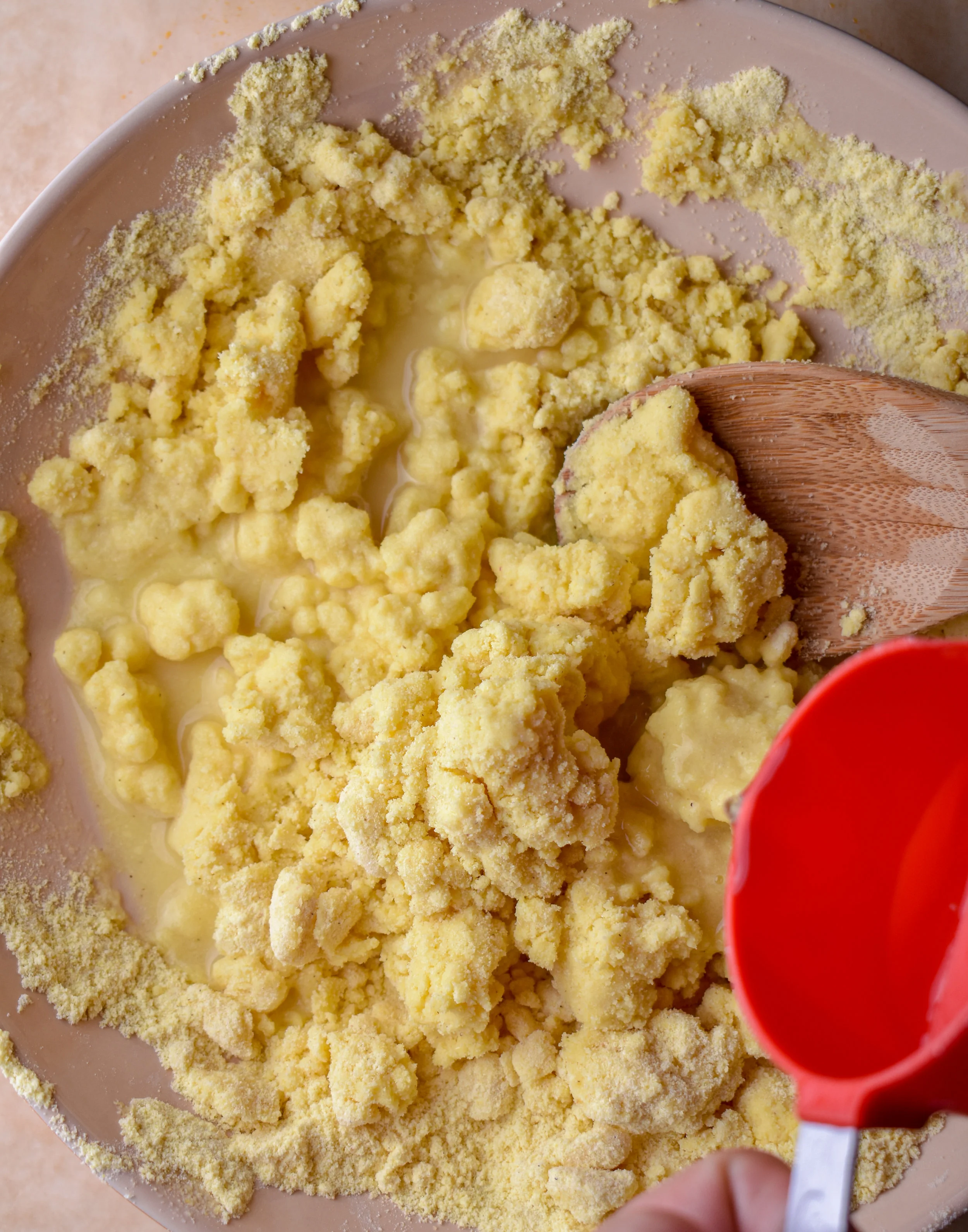 1. Start by mixing together the dry ingredients for the arepas in a mixing bowl. Form a well in the middle and start to pour in the water slowly. As you are pouring, mix it with a wooden spoon slowly.