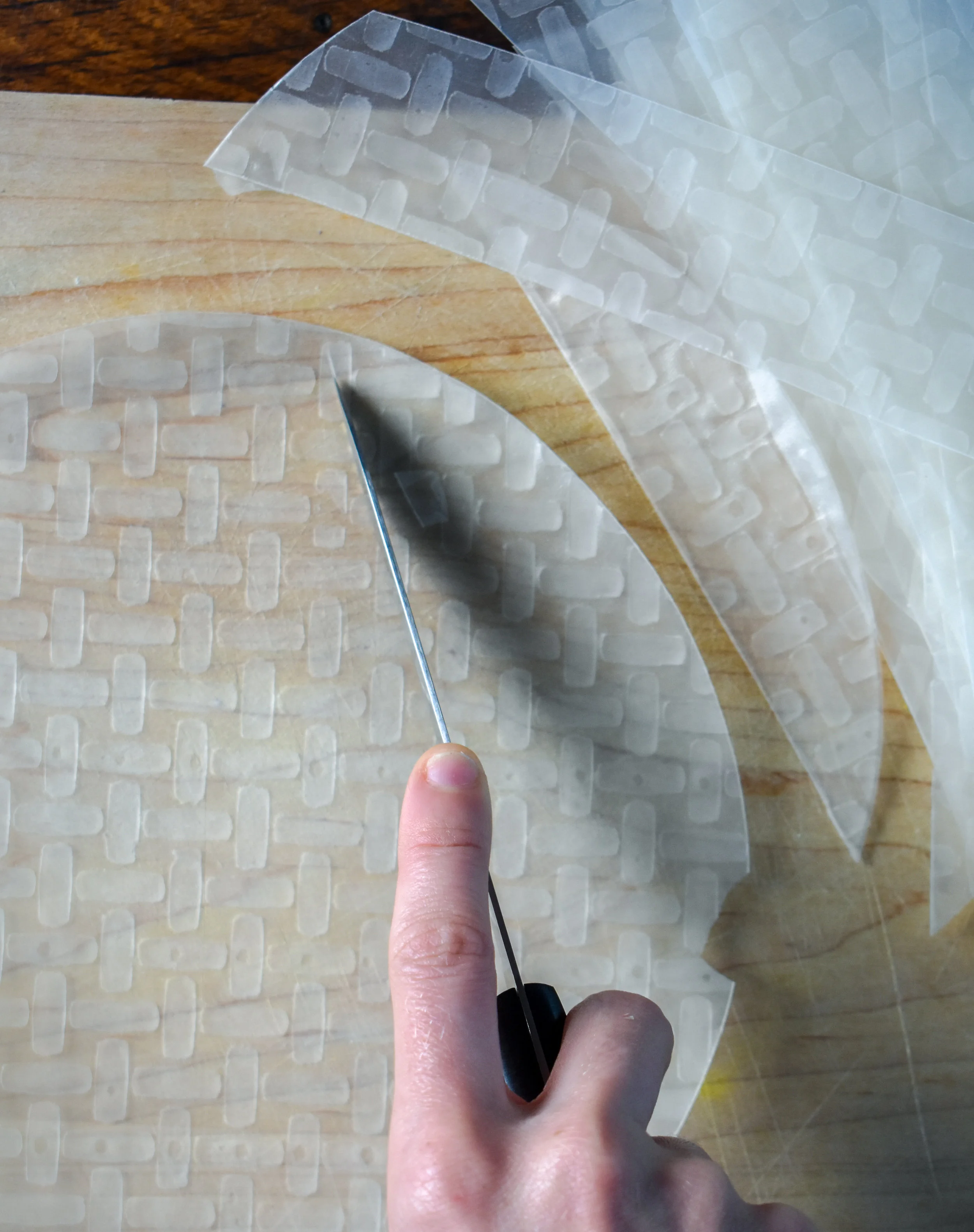 1. To start, using a sharp knife, cut 5 strips about 1.5-2 inches out of each piece of rice paper. Out of 10 sheets of rice paper, you will get about 45-50 pieces. If the paper is cracking, flip it and make your angle higher with your knife as well as try and use a sharper knife on a firm cutting board (wood preferred).