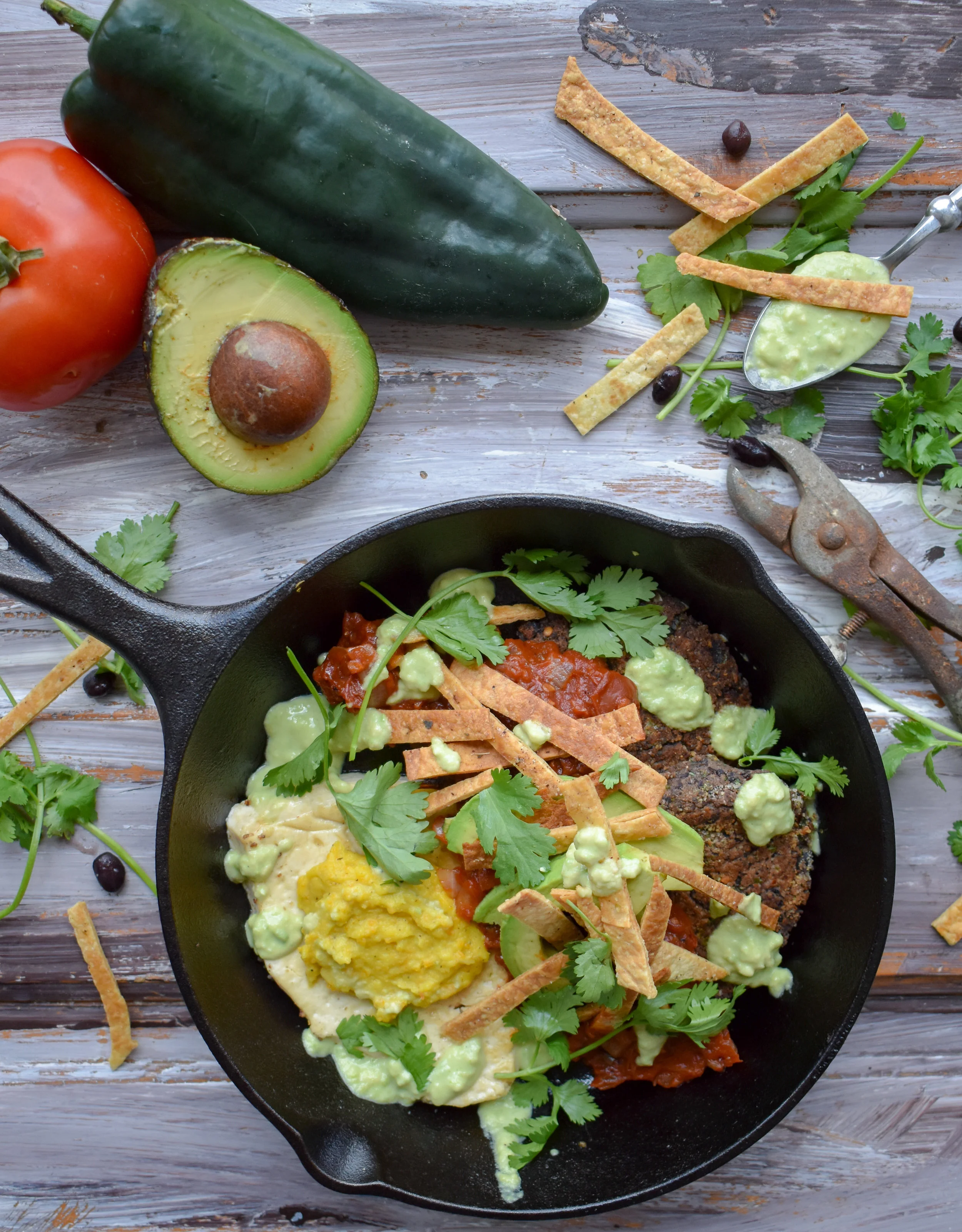 13. To serve, plate with two black bean cakes, one plant egg (add the yolk), pour on 1/4 of the ranchero sauce, add some fresh avocado slices, cilantro, tortilla strips, and drizzle on the avocado crema. YUM YUM YUM YUM YUM !!!!
