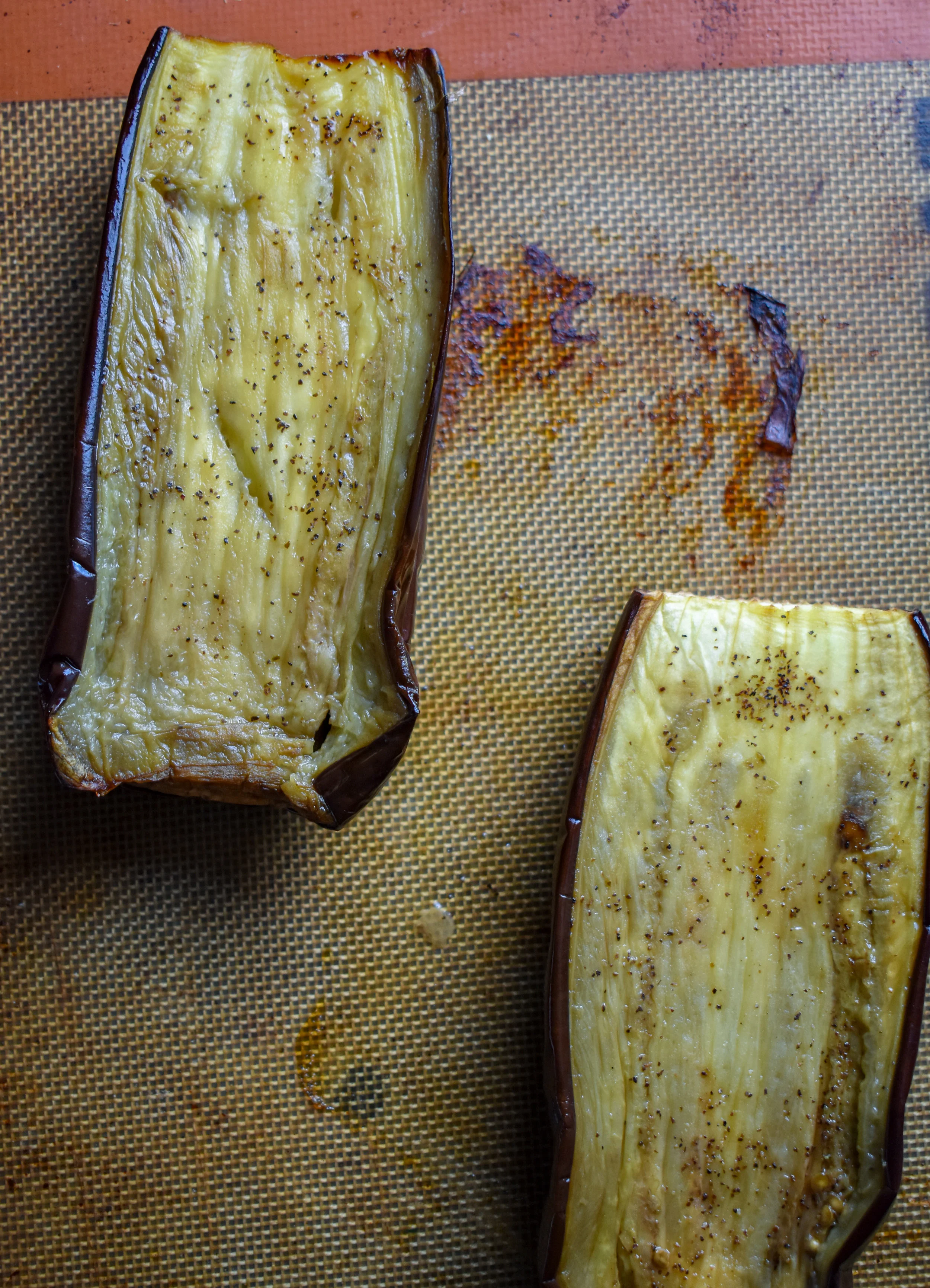 1. Cut your eggplant in 1/2 long ways. Brush on or rub on 1 tbl of olive oil and sprinkle with a pinch of salt + pepper. Place the halves face down on a parchment-lined or silpat-lined baking sheet. Place into the oven at 350F and cook for 40-45 minutes.
