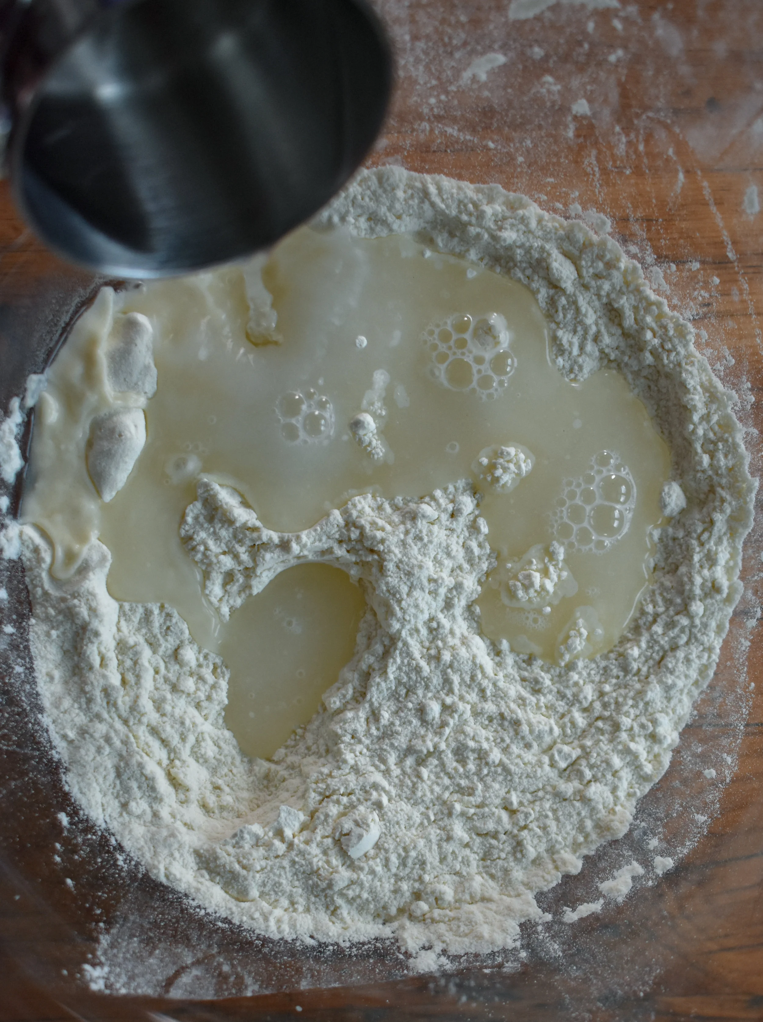 2. While the eggplant cooks, combine the flour + salt for the ravioli dough in a medium mixing bowl. Slowly add the water and olive oil while stirring with a mixing spoon. Mix until all the flour has been worked into the dough mixture.