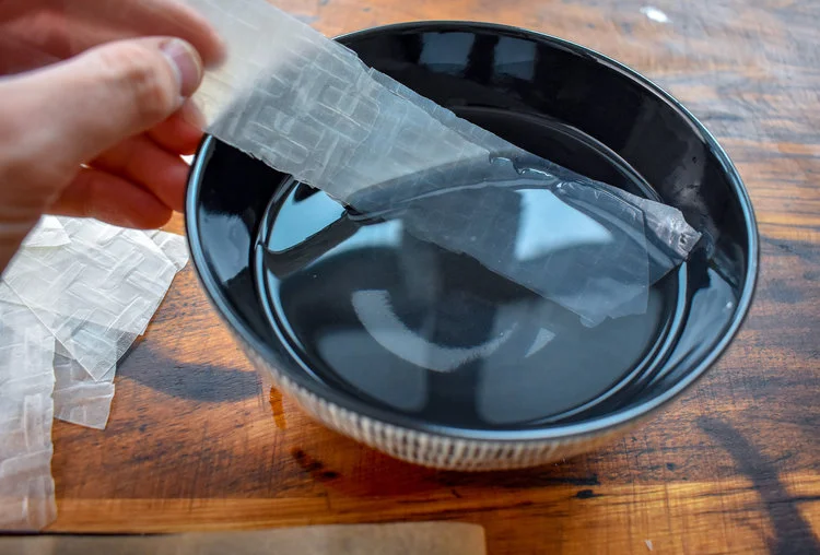 3. Stack two equal sized sheets together and dip into bowl of water to wet the entire strip. Run your fingers down the strip to squeeze out excess water and stack on a parchment lined baking sheet.