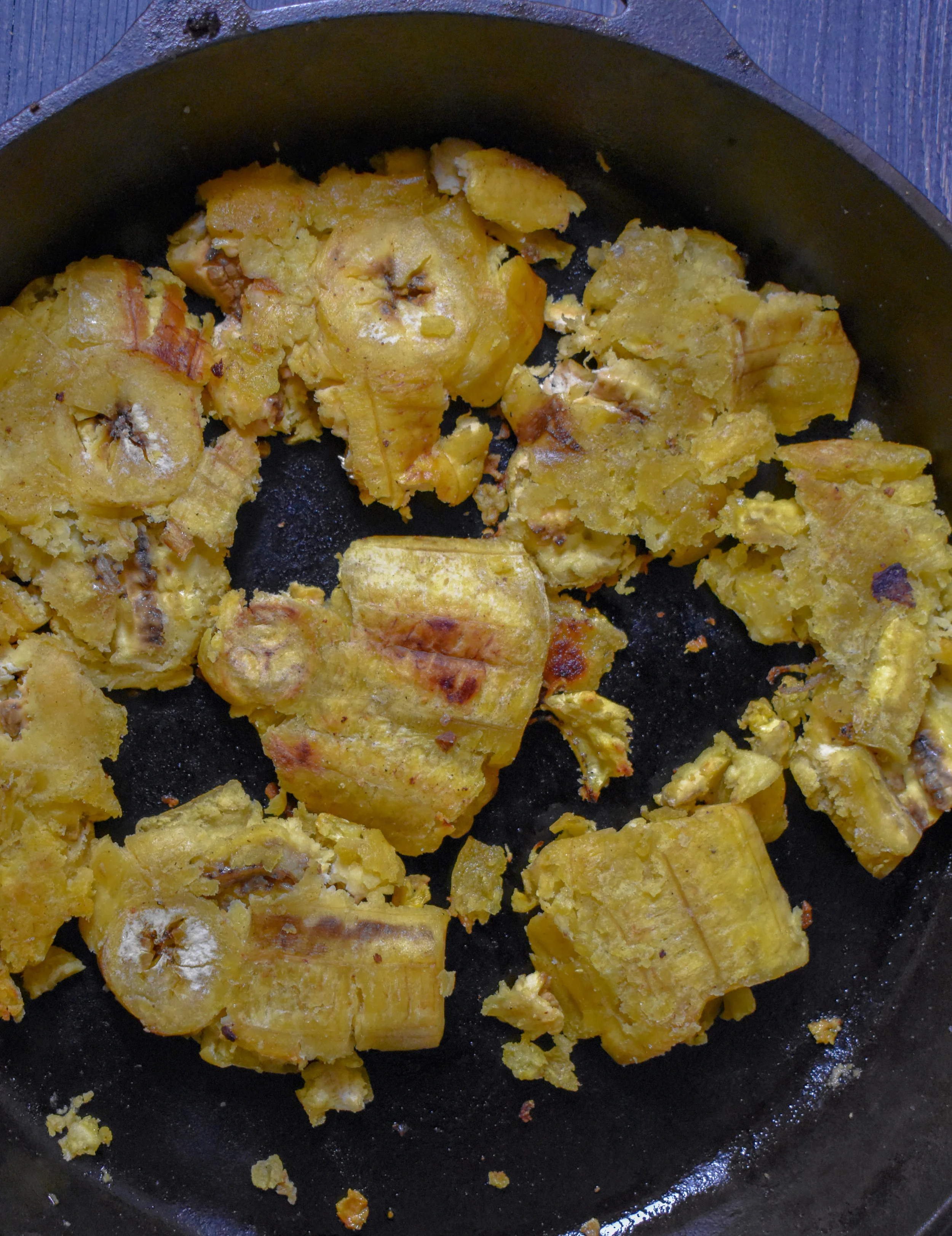 7. With the plantains, use a glass or spatula to smash them down. Take the smashed pieces and throw back into a pan and cook for 1-2 minutes on each side to firm them up.