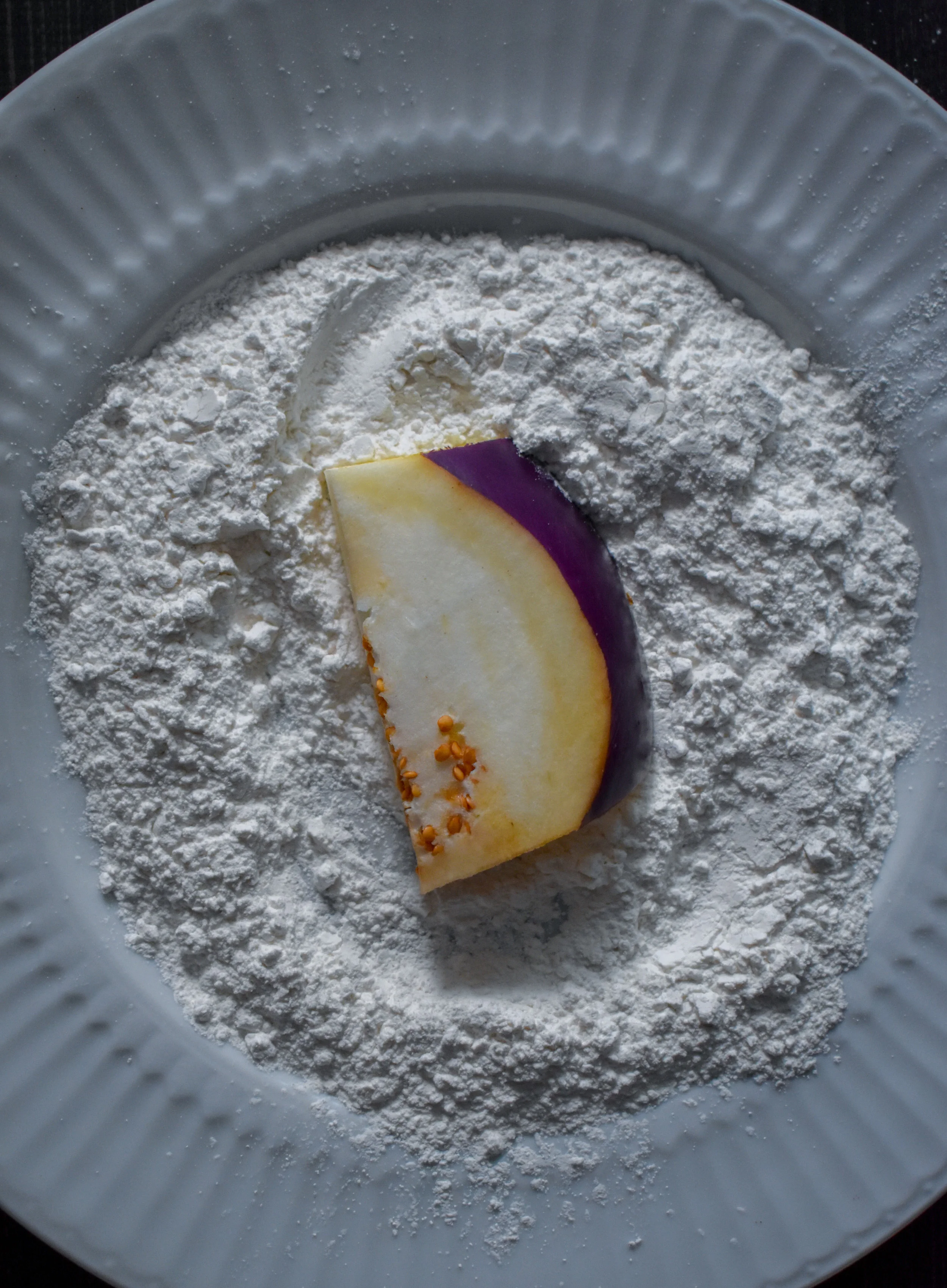 4. While onions and sauce cook, set up three stations for breading and battering. Set up tapioca flour on a plate for dredging. Next step will be flax eggs. Finally, the third plate will be the panko bread crumbs and spices. Start with eggplant cutlet and dredge in tapioca flour.