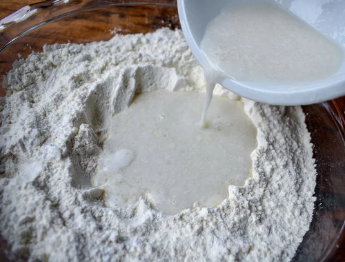 3. Next, pour in the buttermilk slowly while mixing in the milk with a wooden spatula. Gently turning is important an using a soft wooden spoon/spatula.