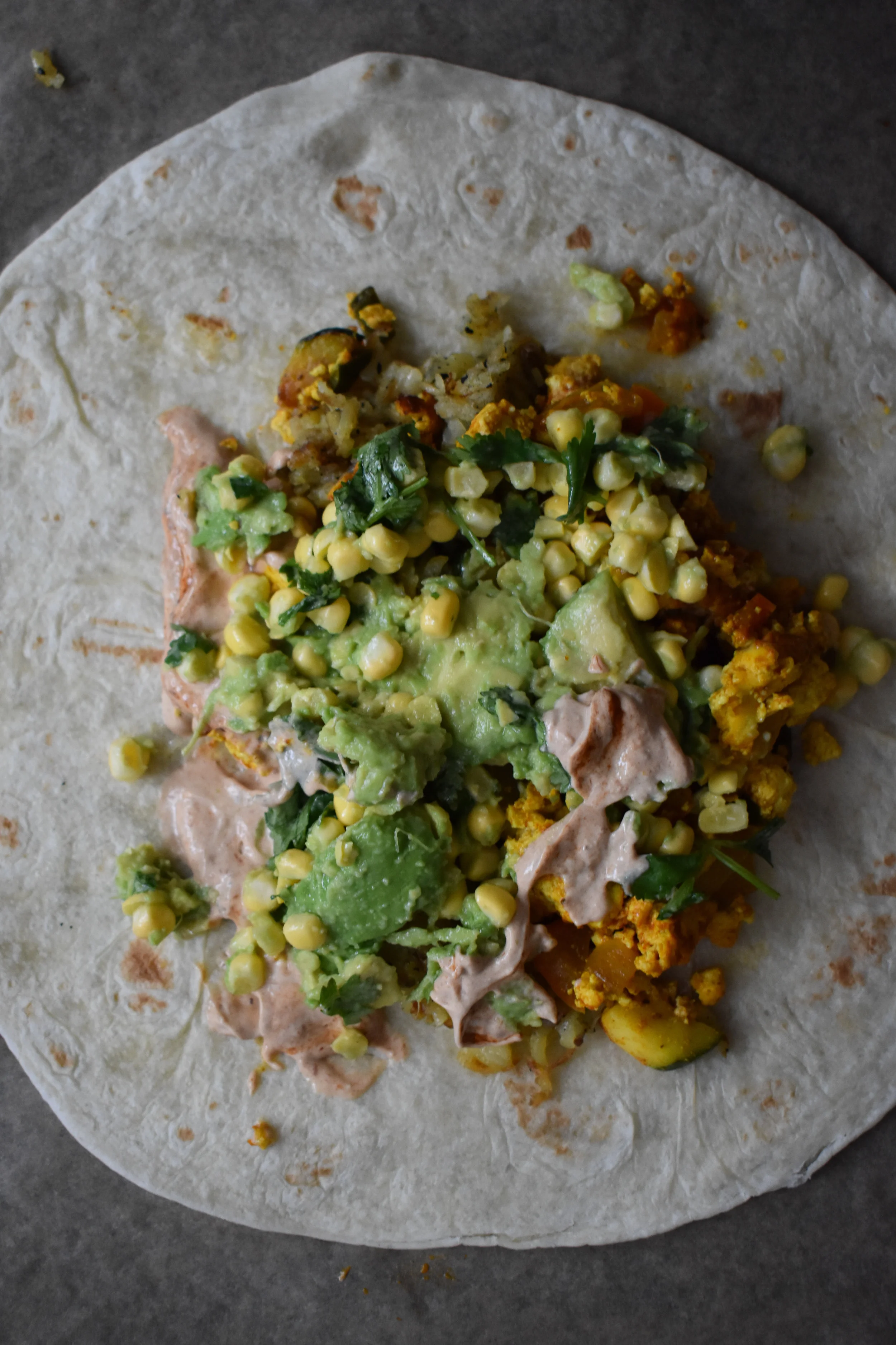 9. Next, add 1/4 the guac, 1/4 the sour cream, and 3 pieces of rice paper bacon. Add some fresh cilantro as well.
