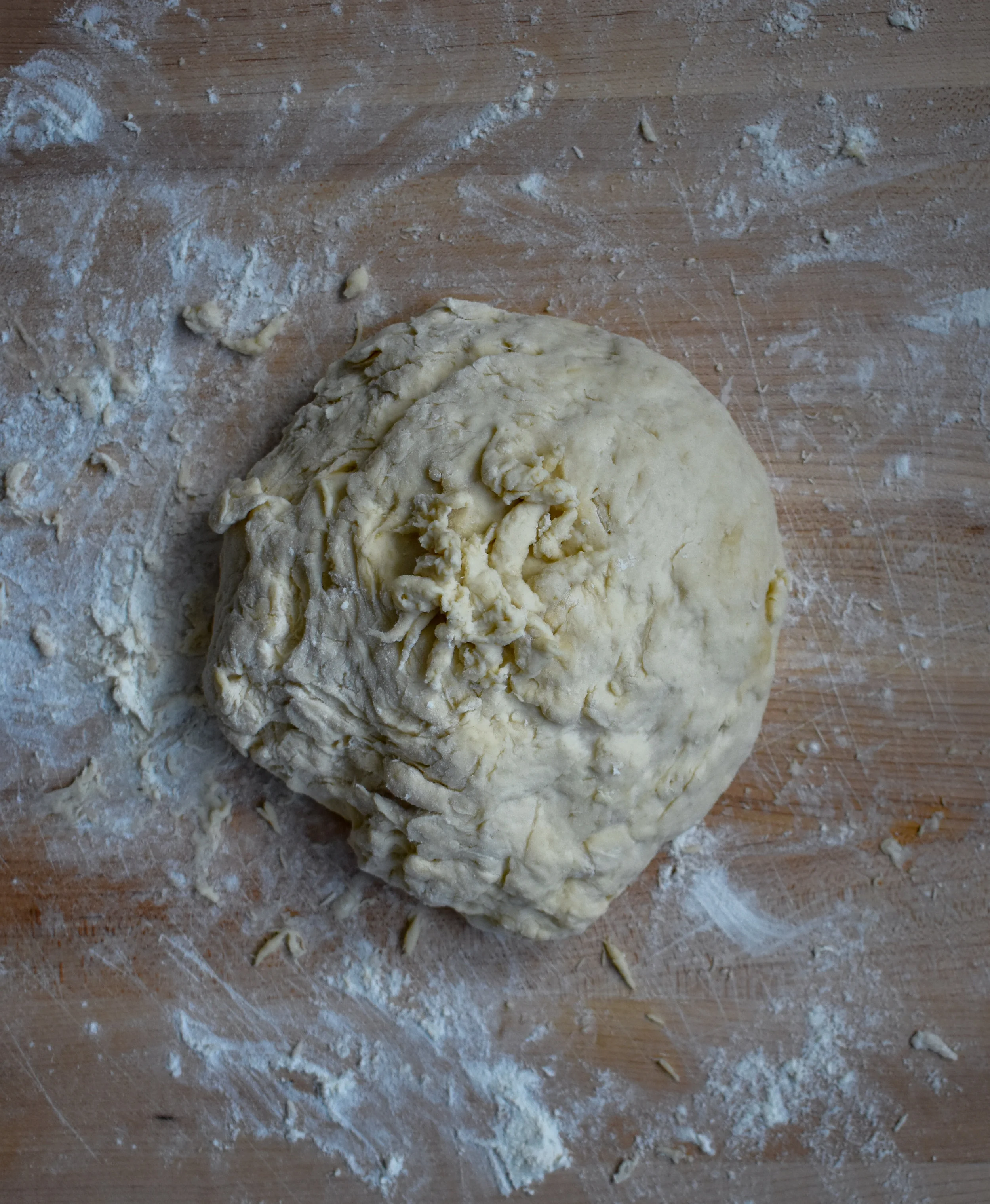3. Put 1/2 cup flour on a clean surface and place dough ball on it. Knead the dough ball and flour for about 4-5 minutes…will become quite sticky. Use a good amount of force (its your workout for the day)! Place the dough ball into a large clean bowl that you rub a bit of oil in. Cover with plastic wrap and leave in a warm place for 50 minutes. The ball will double in size.