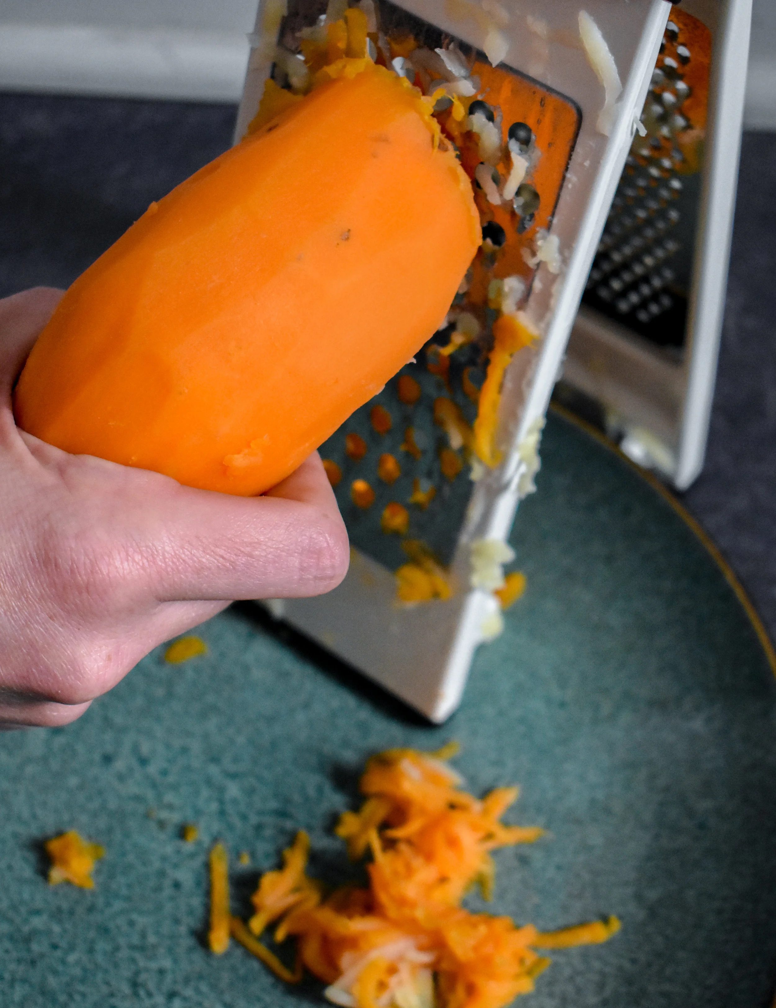 2. Using a box grater or hand grater, grate the potatoes down onto a large plate.