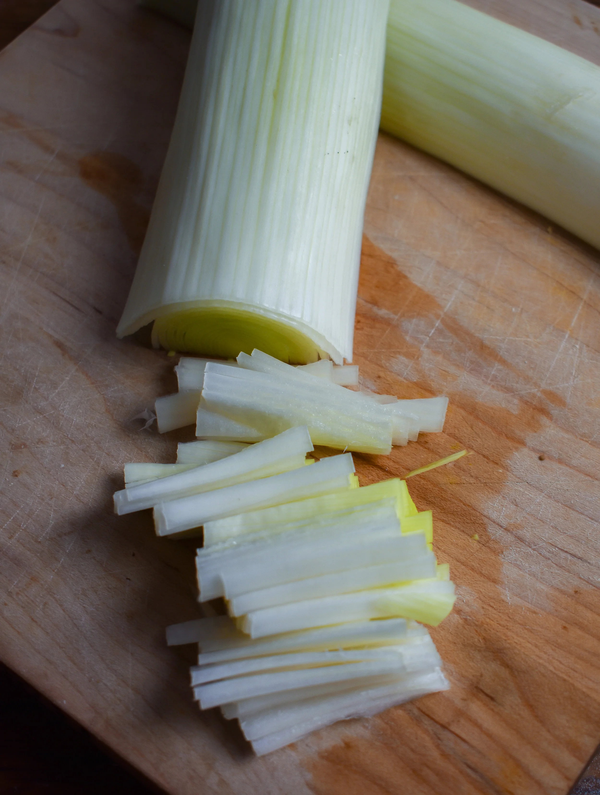 4. For the leeks, place a pan on the stove over medium heat with the oil. To chop the leeks, cut in half, then in 2 inch segments, then cut longwise to make into small matchsticks.