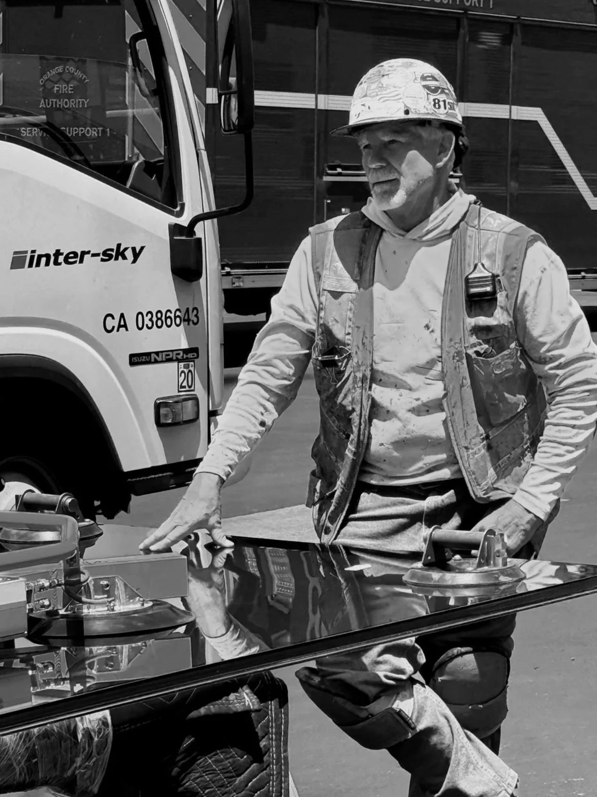 An inter-sky crew member on a job site waiting to raise a pane of glass with a crane