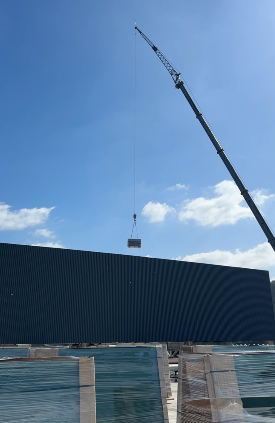 A Large Crane shown lifting a crate of glass onto a building