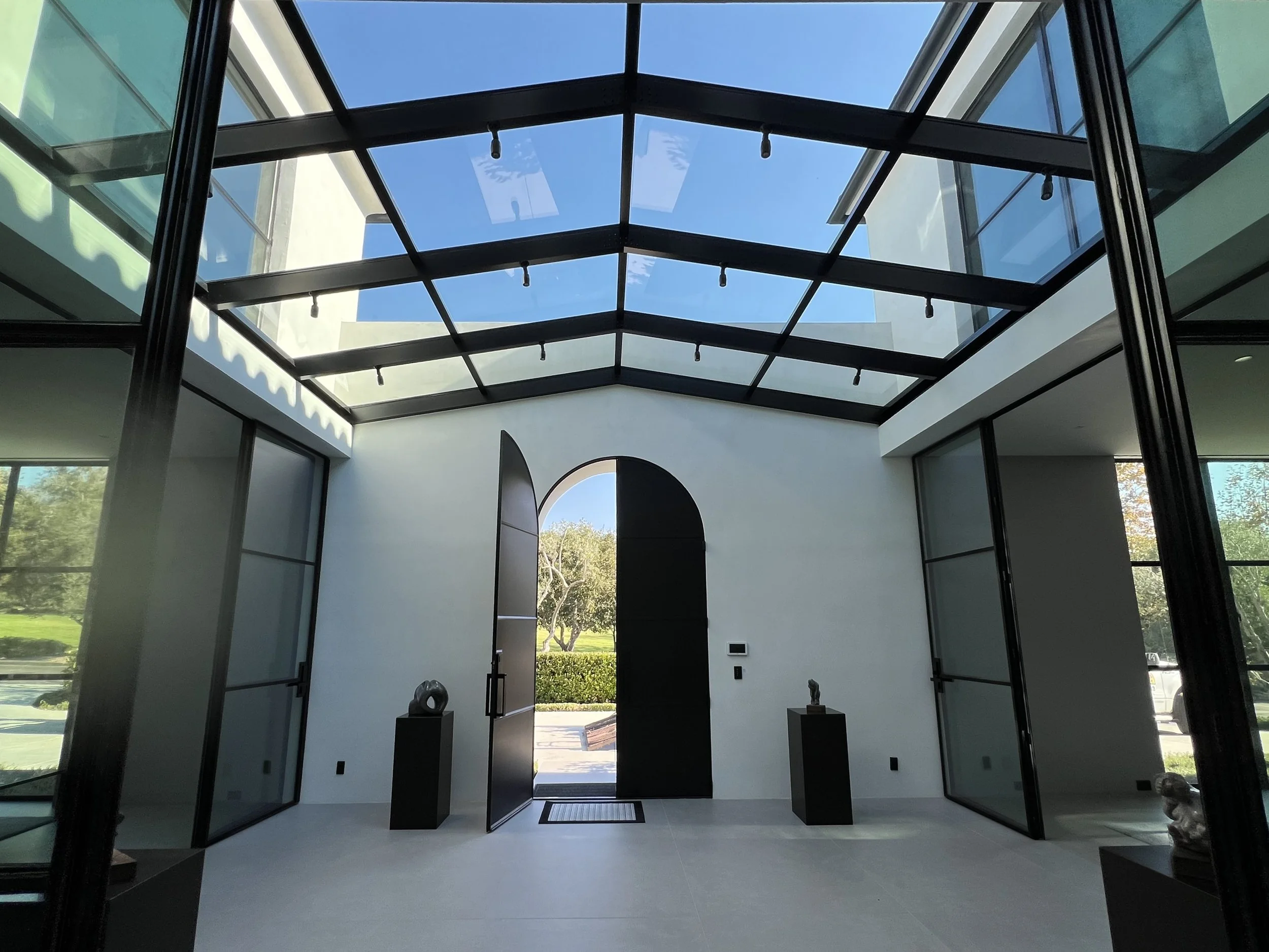 Modern home entryway with a large glass ridge skylight and black frame.