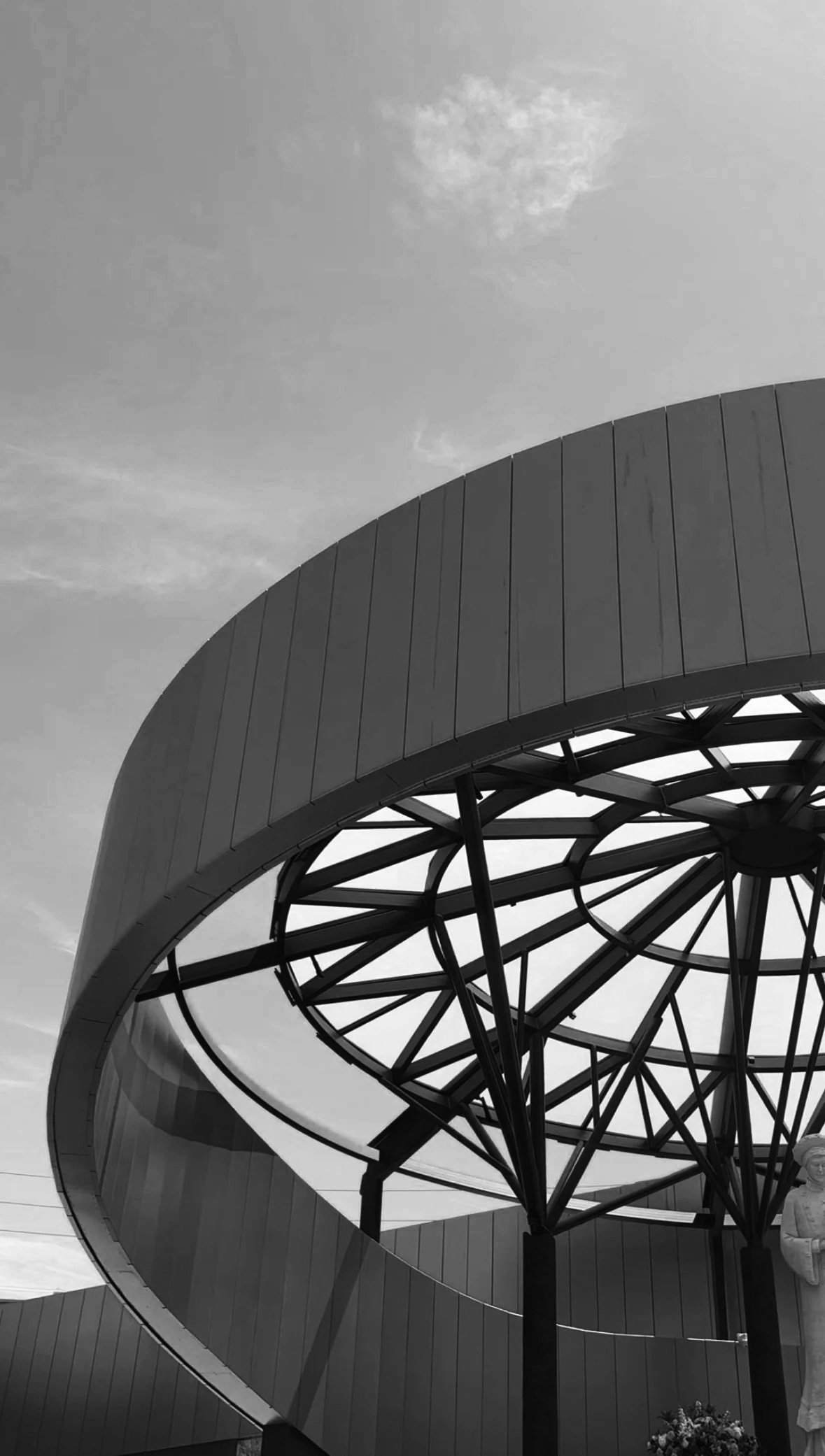 An architectural elliptical canopy of glass viewed from below.