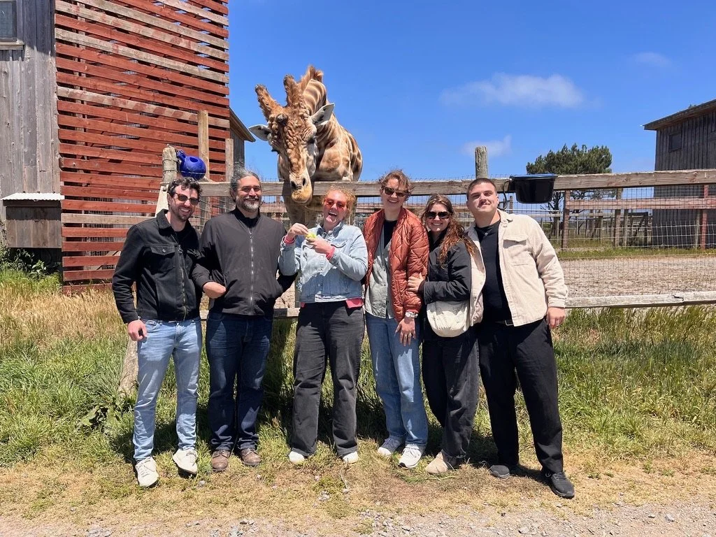 Group of six people posing in front of a nubian giraffe at B. Bryan Preserve in Point Arena, Califronia. 