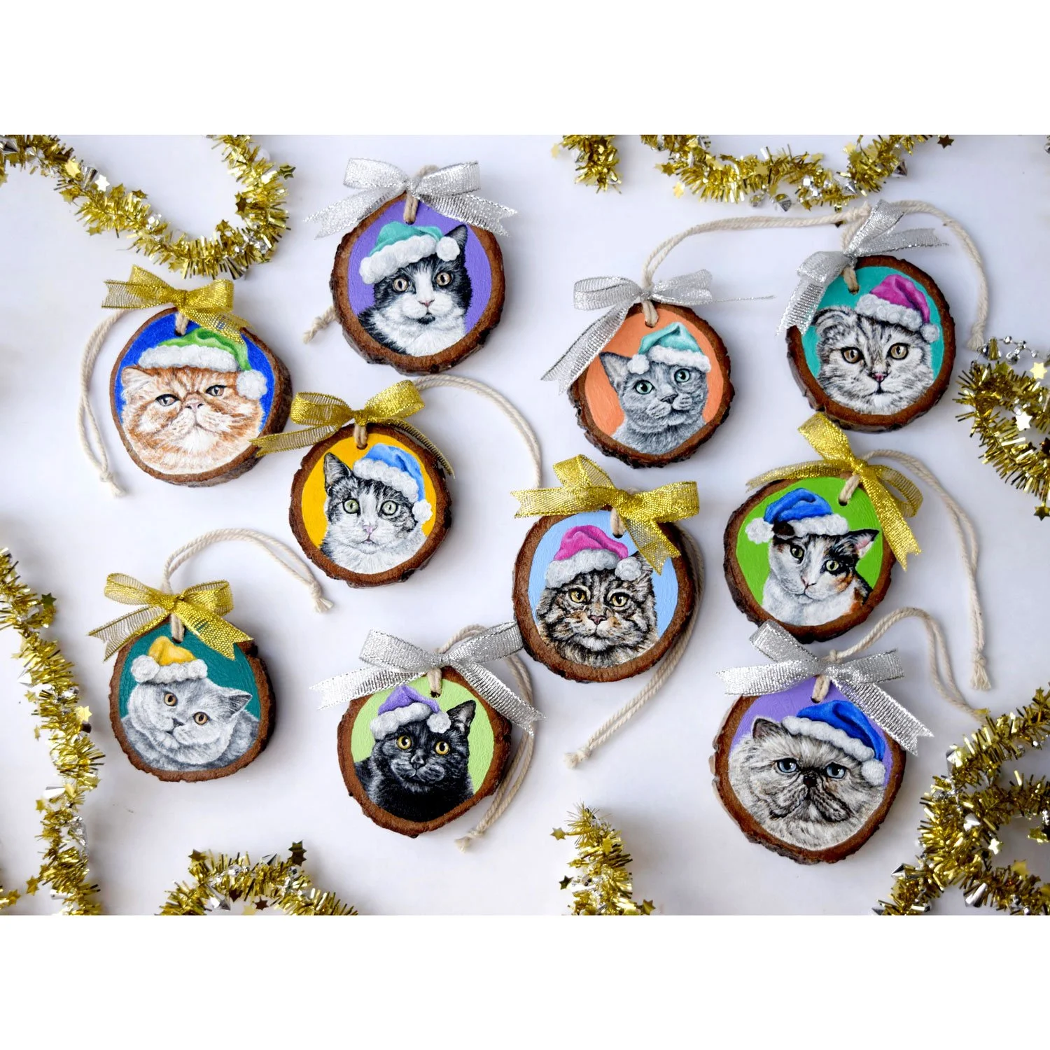 Custom acrylic cat portraits of cats wearing Santa hats of all different colors on wood ornaments by Emma Sage Fine Art, Los Angeles.