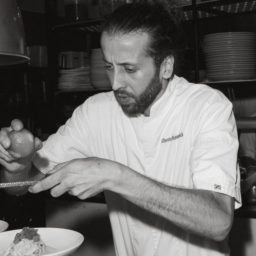 Chef Alberto Vitassovich plating a dish in his kitchen