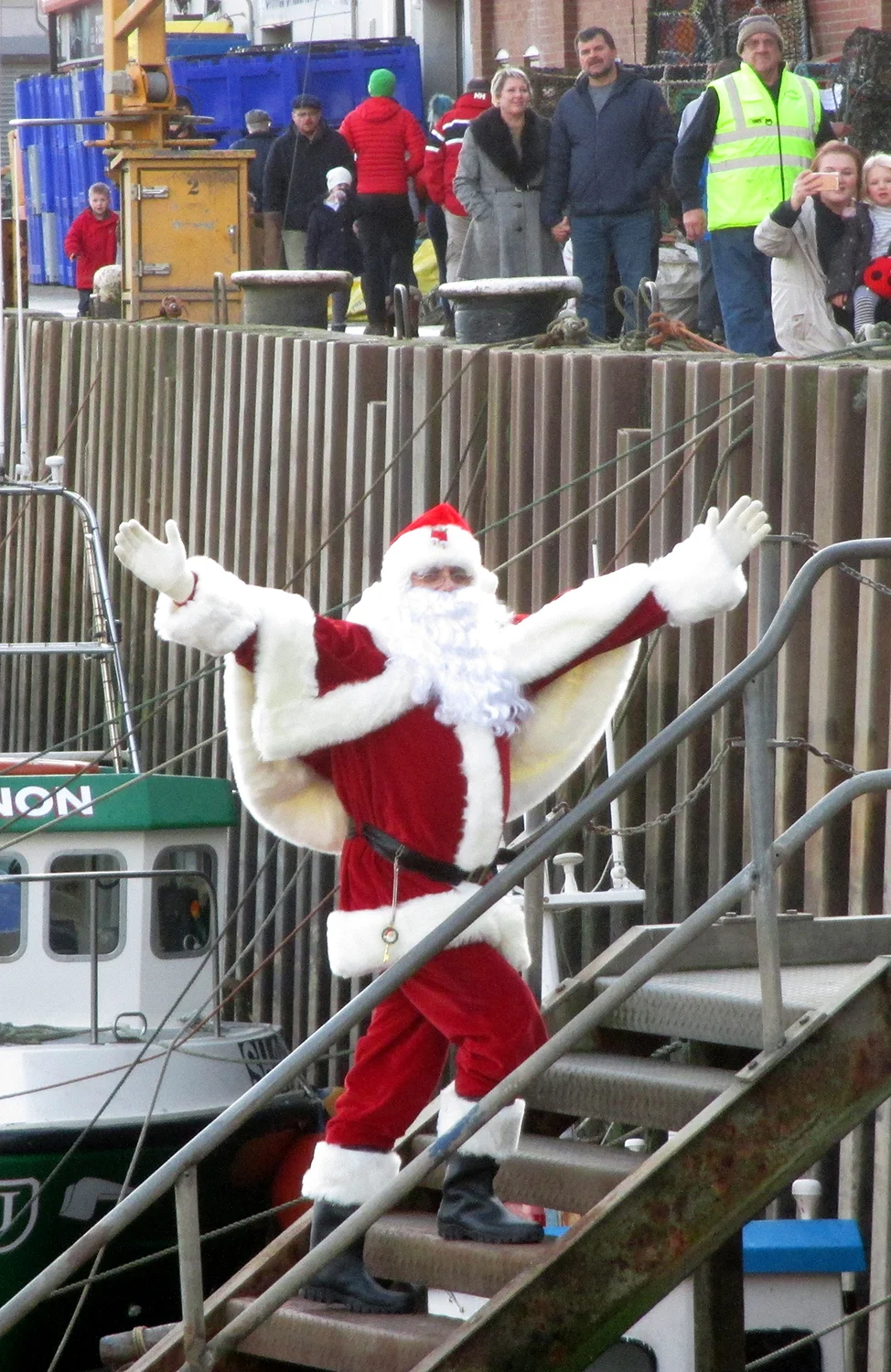 Santa climbs the steps from the boat to the pier
