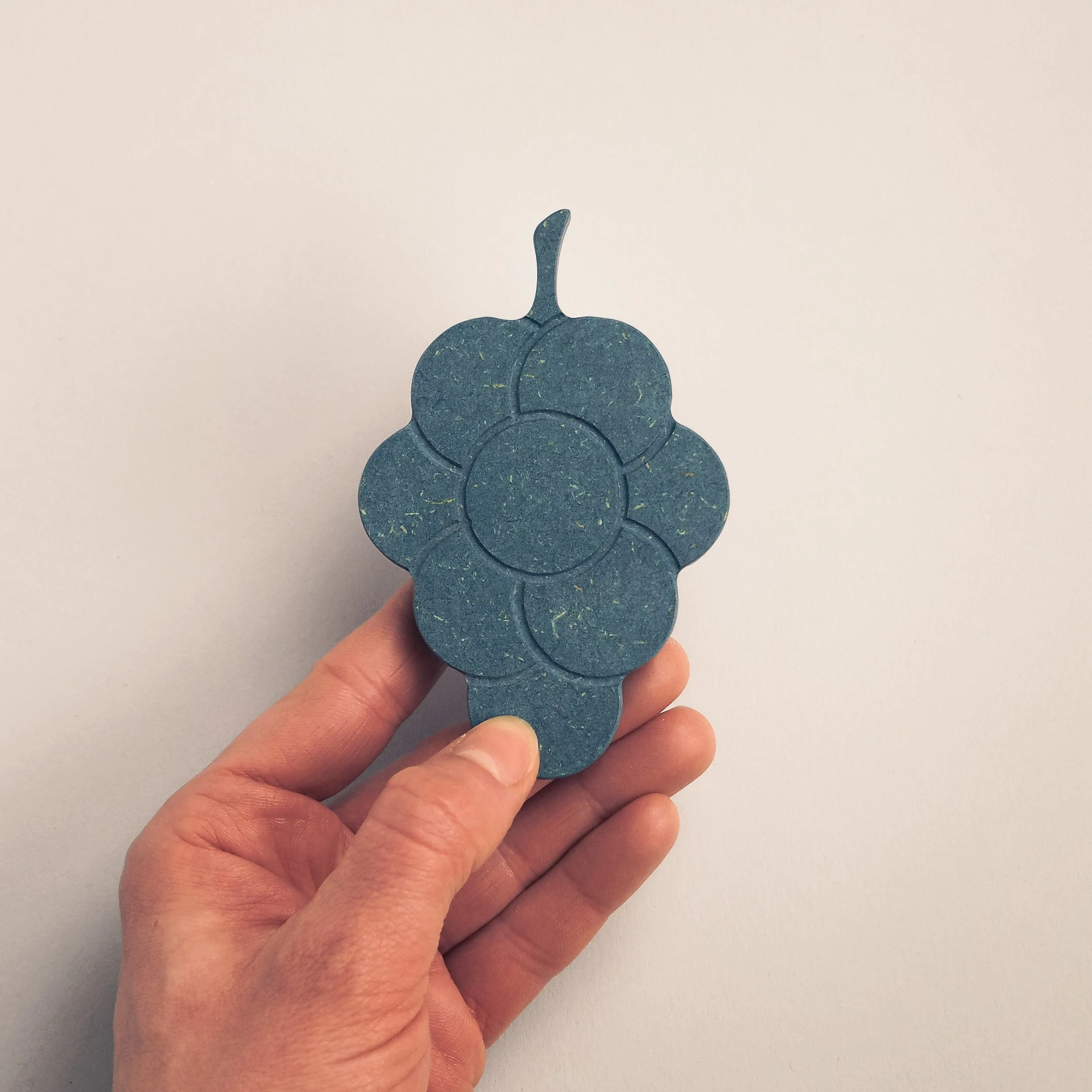 model hand holding blue grape wooden toy fruit