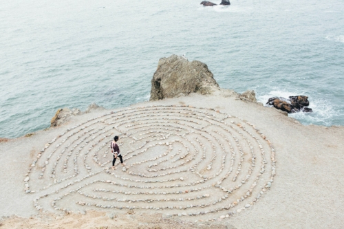 Zen rock meditation circle with woman walking through on seashore