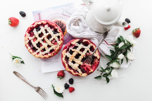 Mini cherry pies with lattice top on white table over recipe