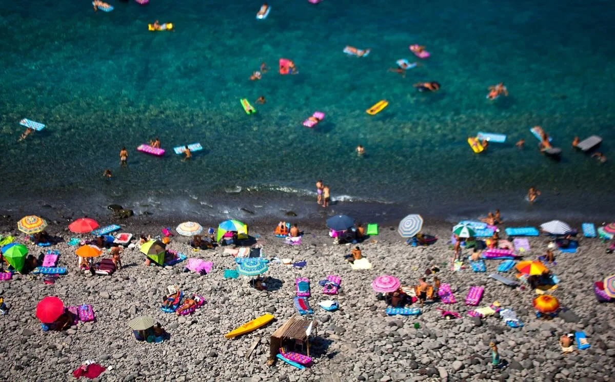 People, umbrellas, beach towels, and sea mattresses creating colorful patterns and geometric rhythms. When you zoom in, you find life unfolding in every detail. #italiansummer