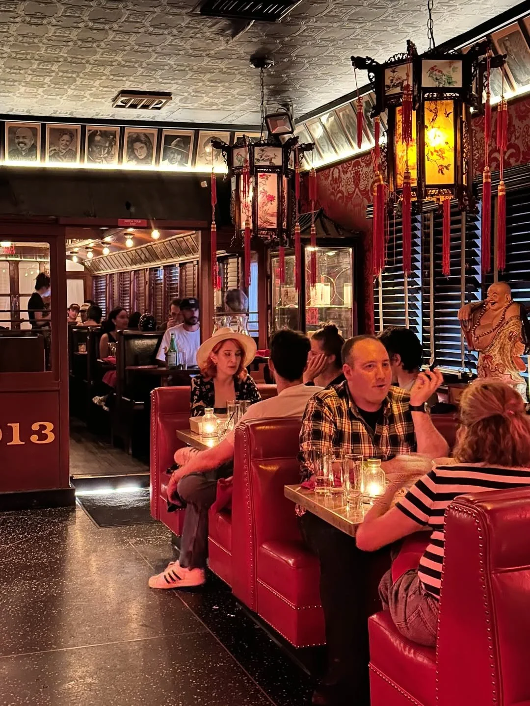 Guests dine in red leather booths beneath hanging lanterns beside The Formosa Cafe's historic red trolley car inside the main dining room.