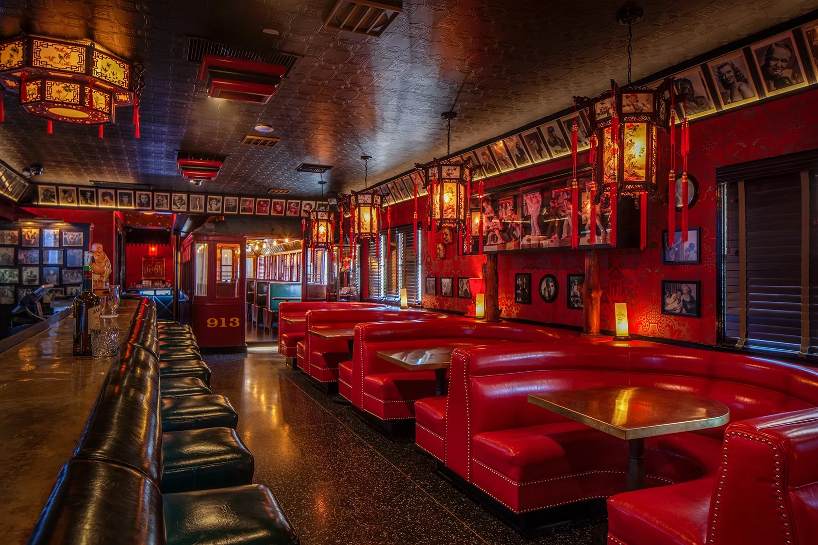 The Formosa Cafe with green bar chairs and red sofas with frames on the walls and Chinese decor.