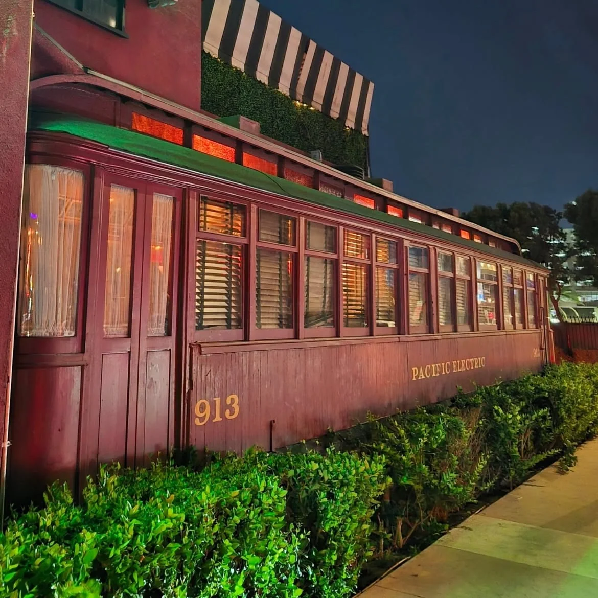 Exterior of a vintage red Pacific Electric trolley car attached to the historic Formosa Cafe building.