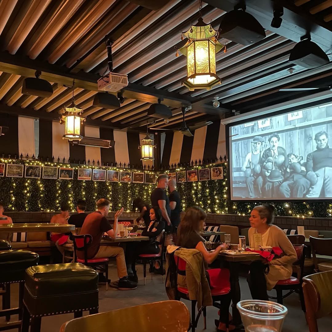 Interior of The Formosa Cafe with warm lantern lighting, classic red booths, and diners seated at tables