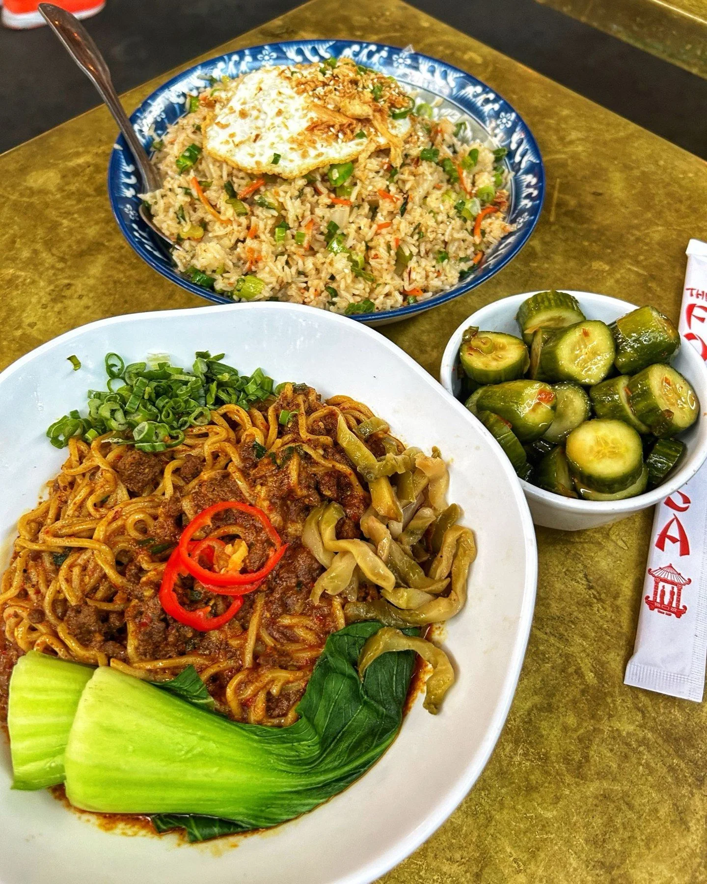 Spicy noodles bowl with bok choy, fried rice, and cucumber salad at The Formosa Cafe.