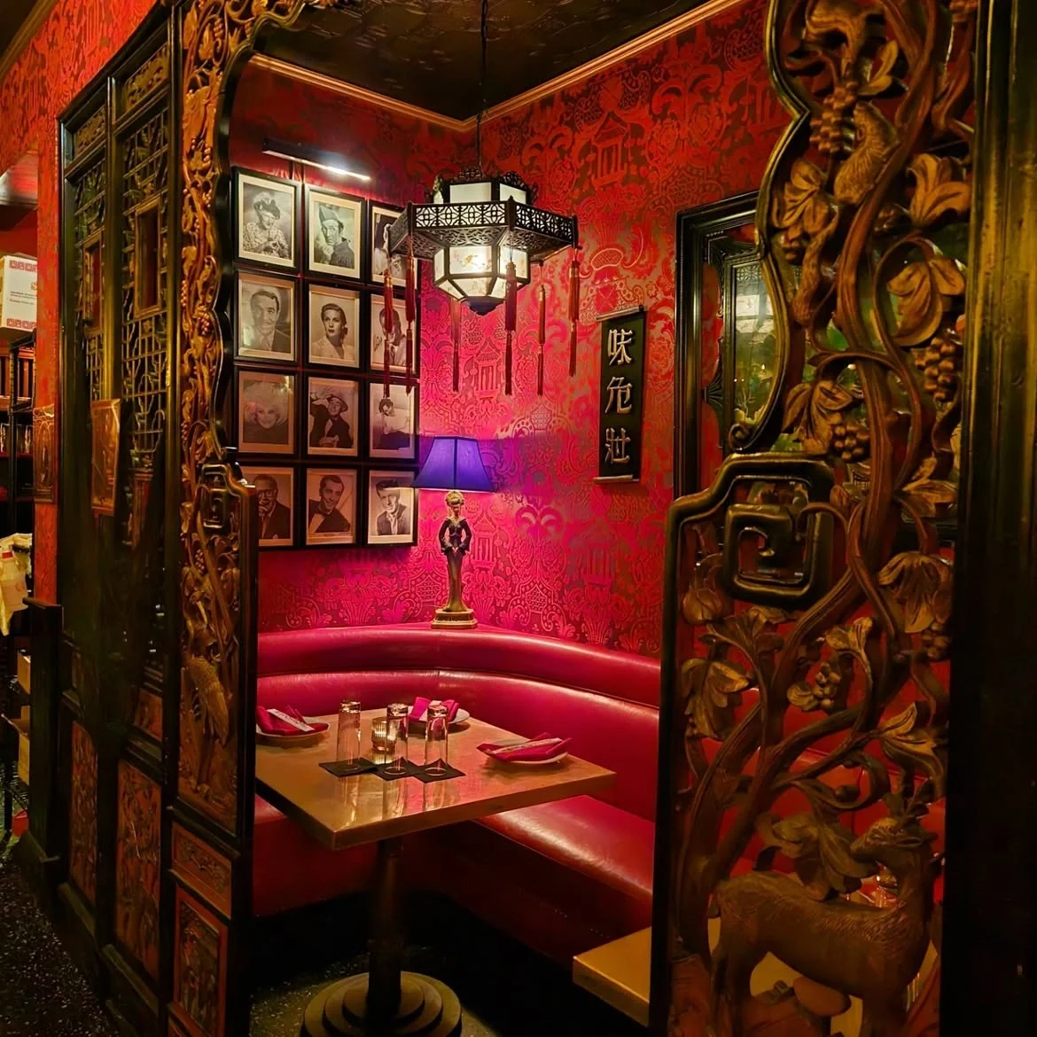 Red booth framed by a carved wooden archway and walls decorated with Old Hollywood portraits at The Formosa Cafe.