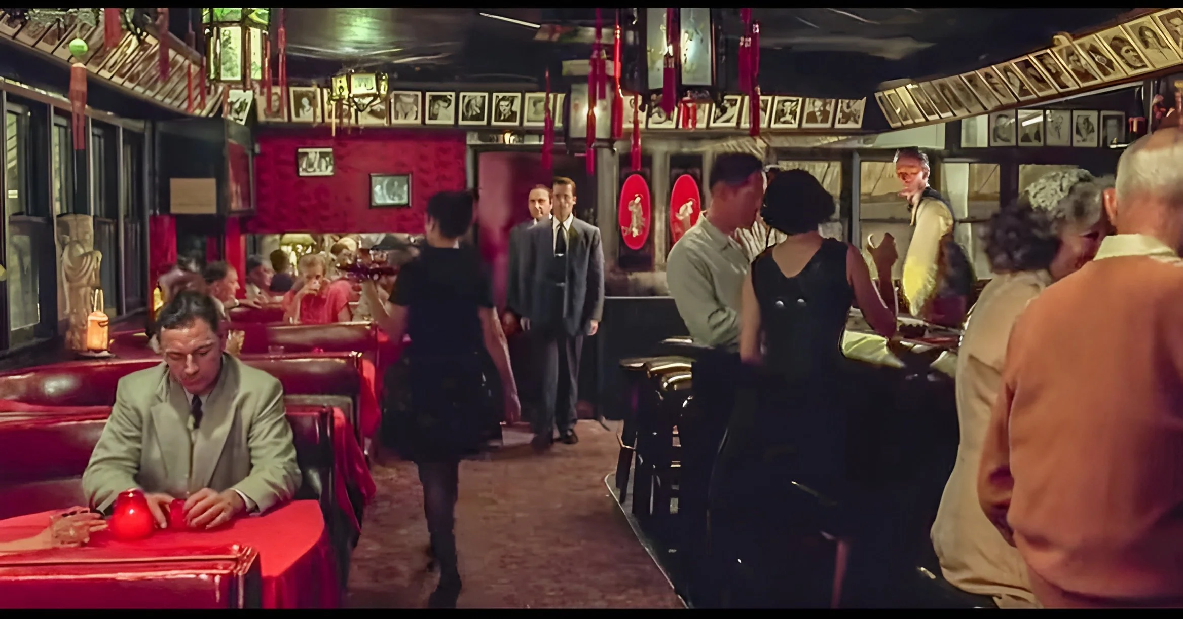 Historic wide shot of The Formosa Cafe showing classic red booths, a wall of celebrity headshots, and people.