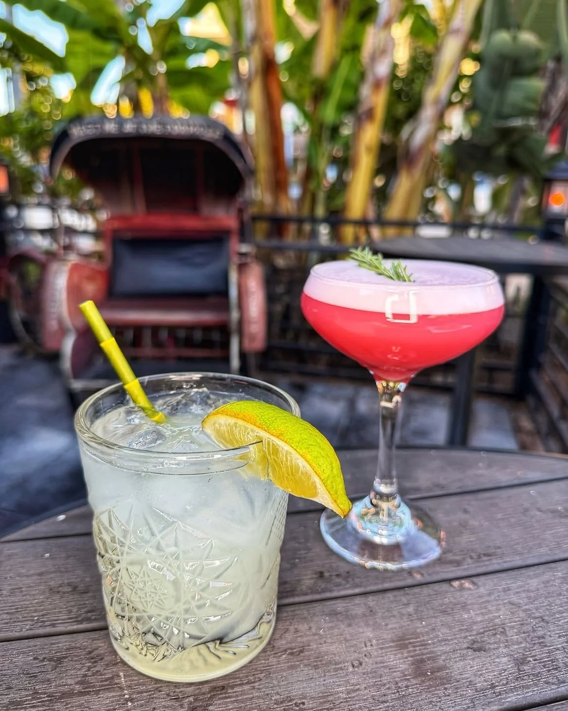 Two signature cocktails served on an outdoor table beside the historic vintage trolley at The Formosa Cafe.