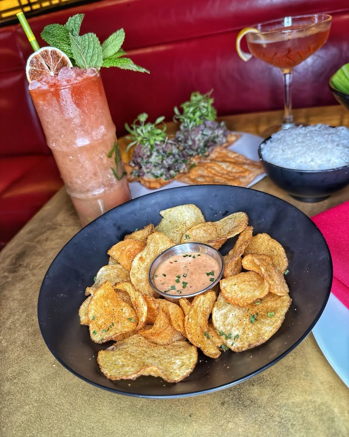 A plate of crispy potato chips with dip and tropical cocktails on a table at The Formosa Cafe.