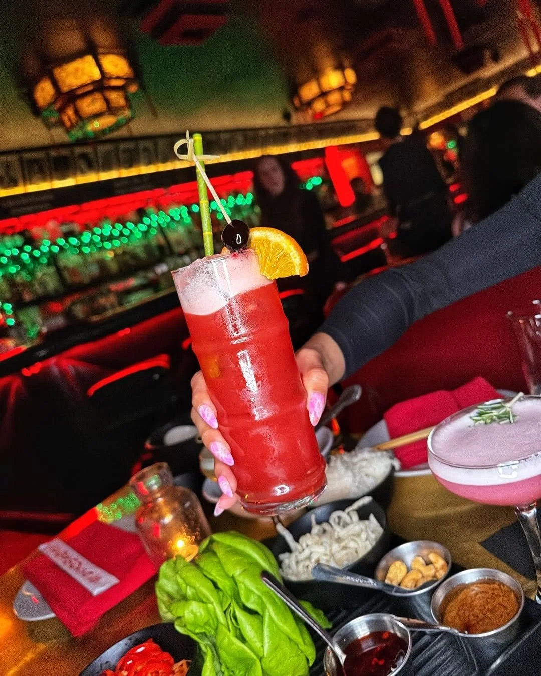 Colorful red cocktail garnished with fruit alongside shareable Chinese-American dishes at The Formosa Cafe in West Hollywood.