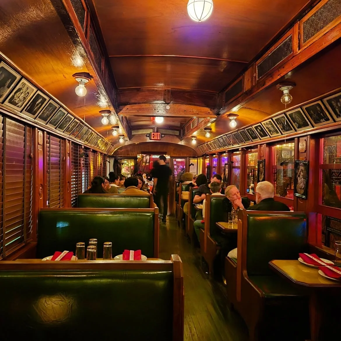 Wood-paneled train car dining room at The Formosa Cafe with green booths and framed vintage photos.