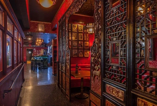 Restaurant interior with carved wooden screens, red leather booths, and celebrity headshots at The Formosa Cafe.